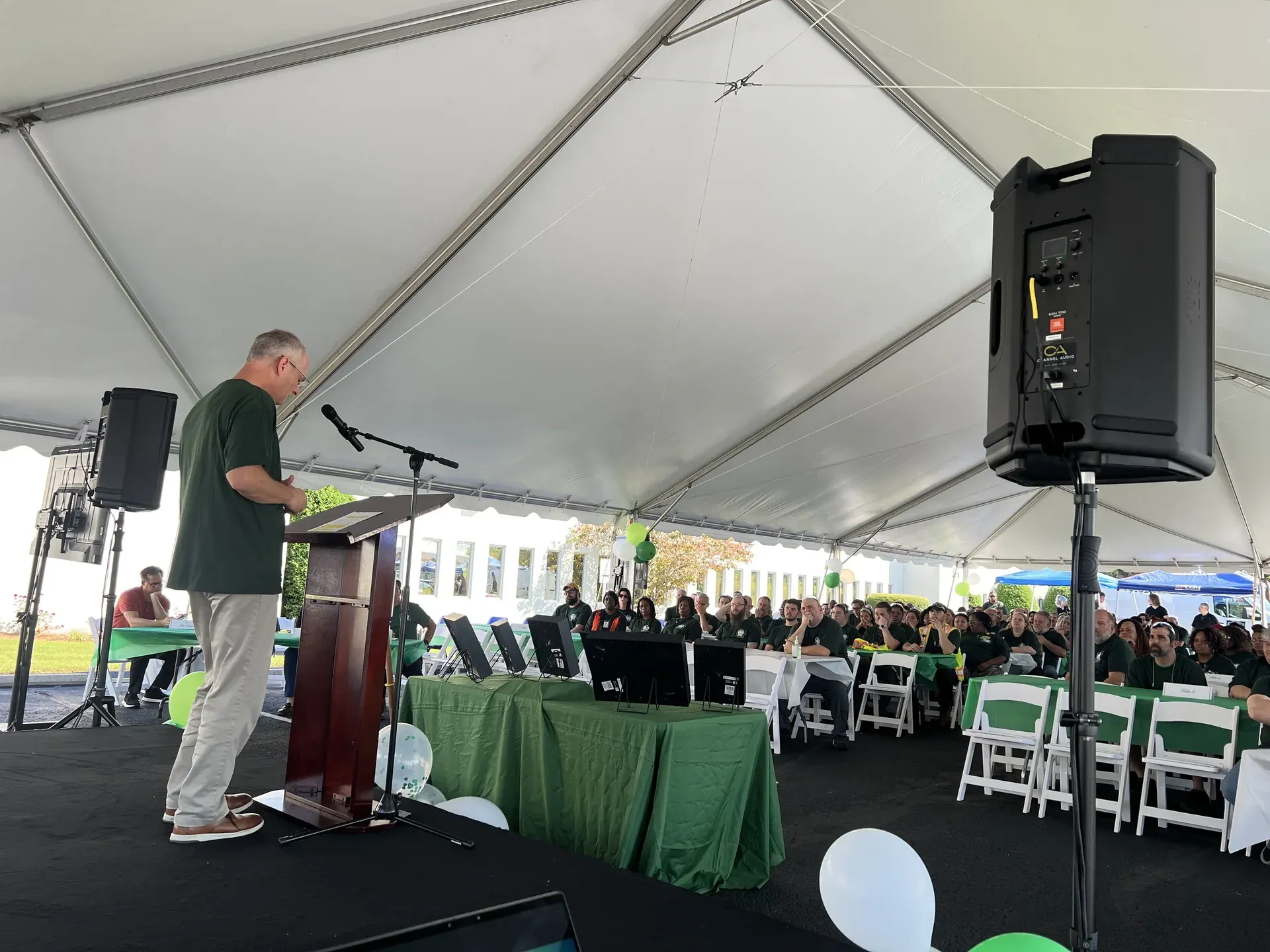 Outdoor tent event with TV display and audio seating setup