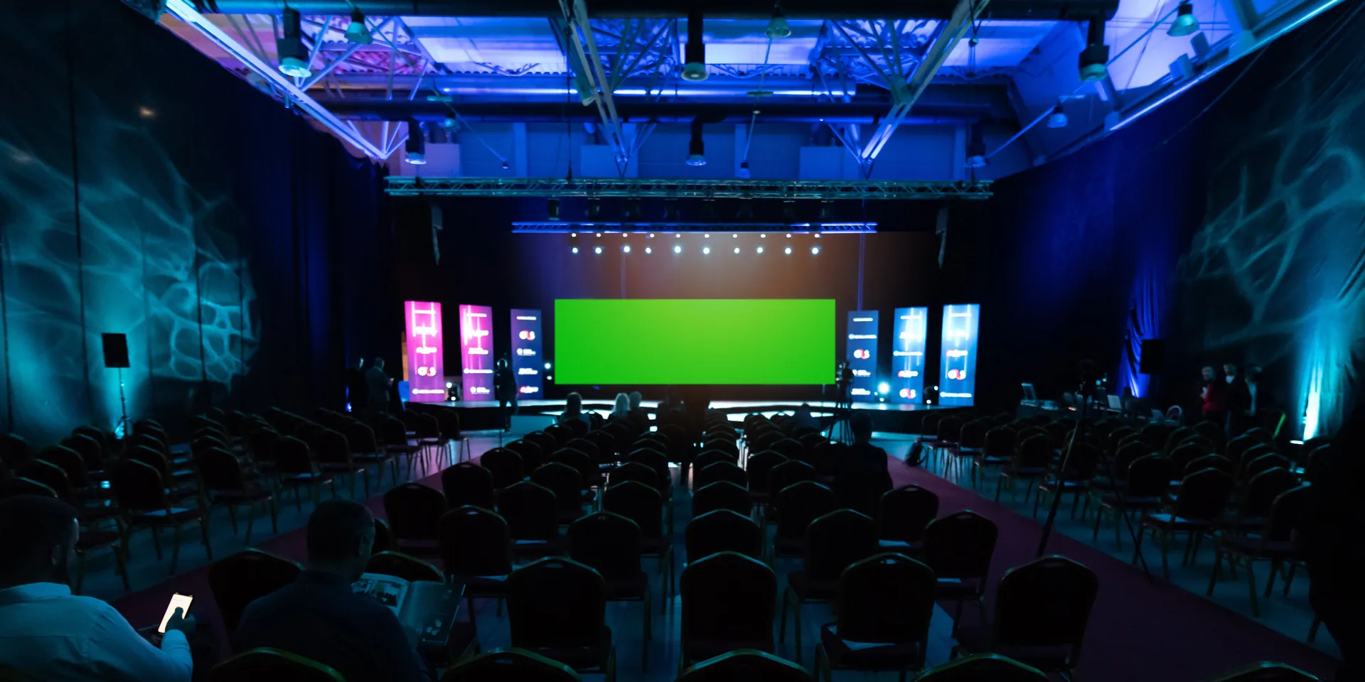 Professional event stage with lighting, large screens, sound system and accessible seating positioned for clear sightlines