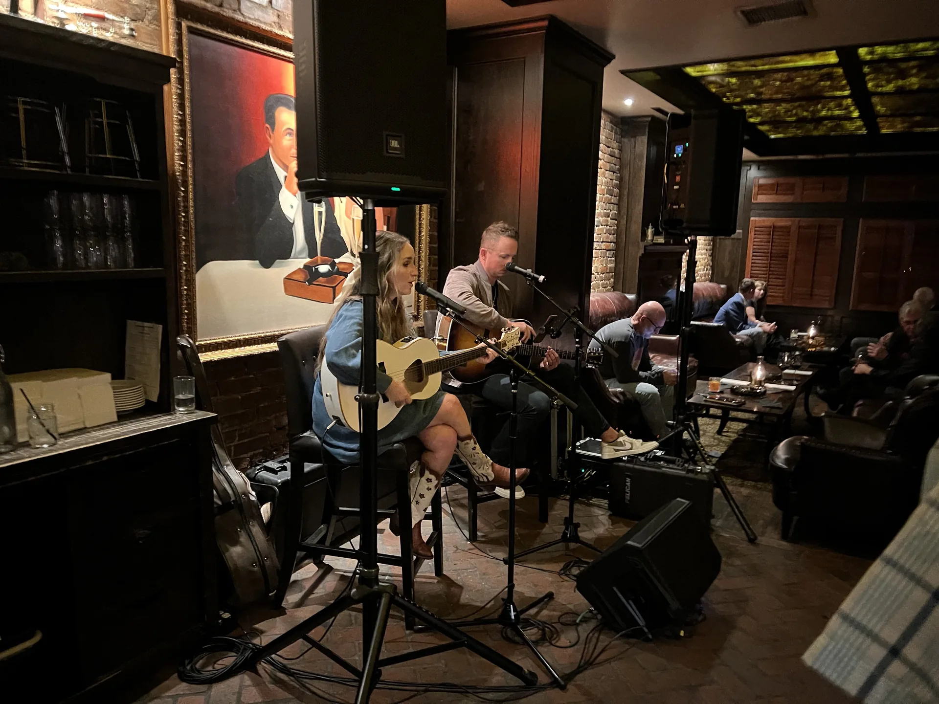 Acoustic guitar duo performing live into microphones at a Nashville bar event