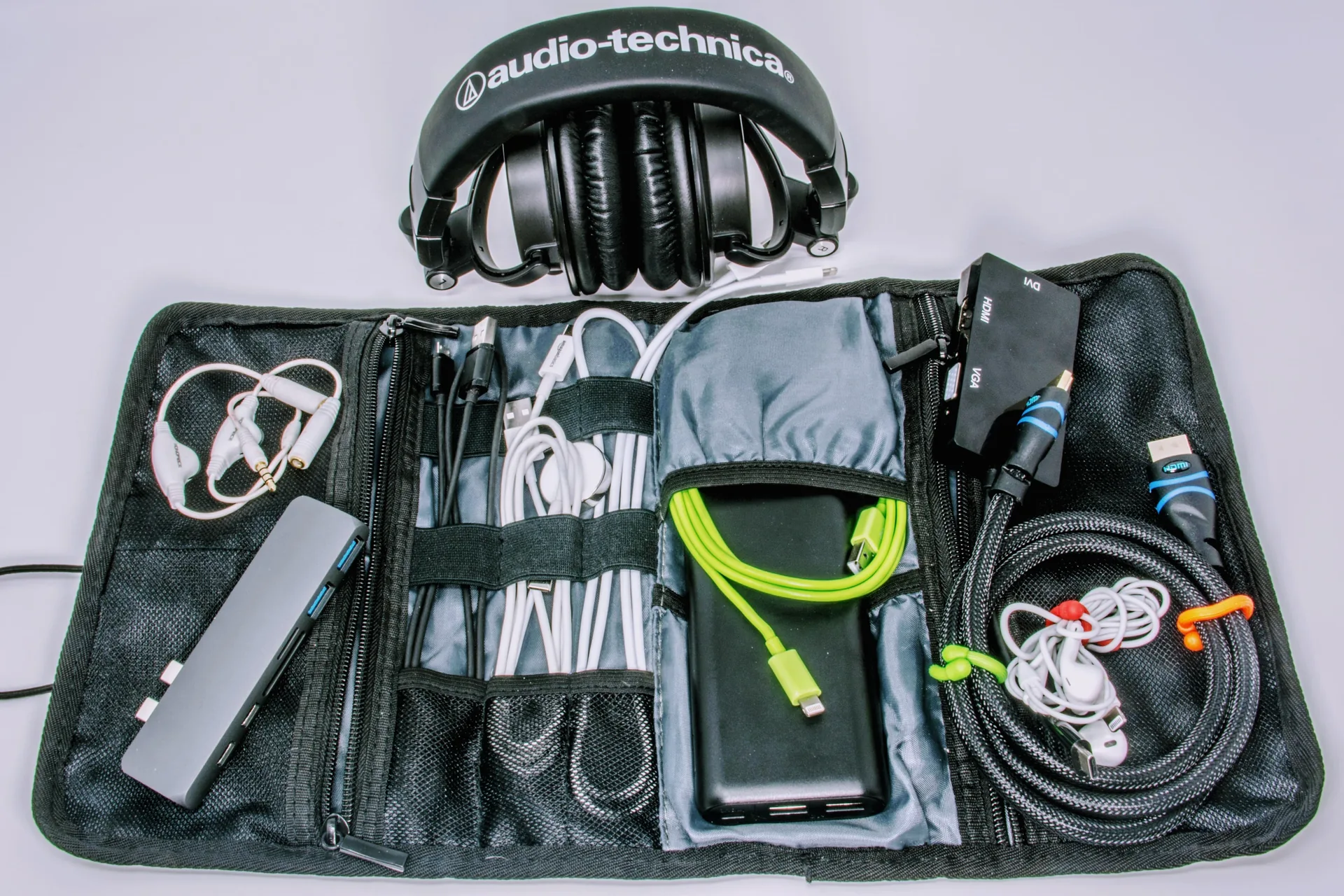 Tech organizer bag containing various adapters, cables, headphones and dongles