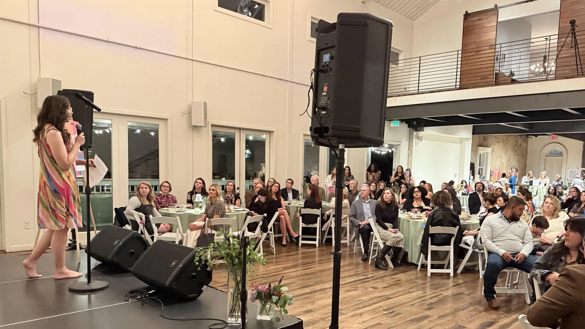Fundraiser event audience viewing presenter with professional JBL speakers and stage monitors