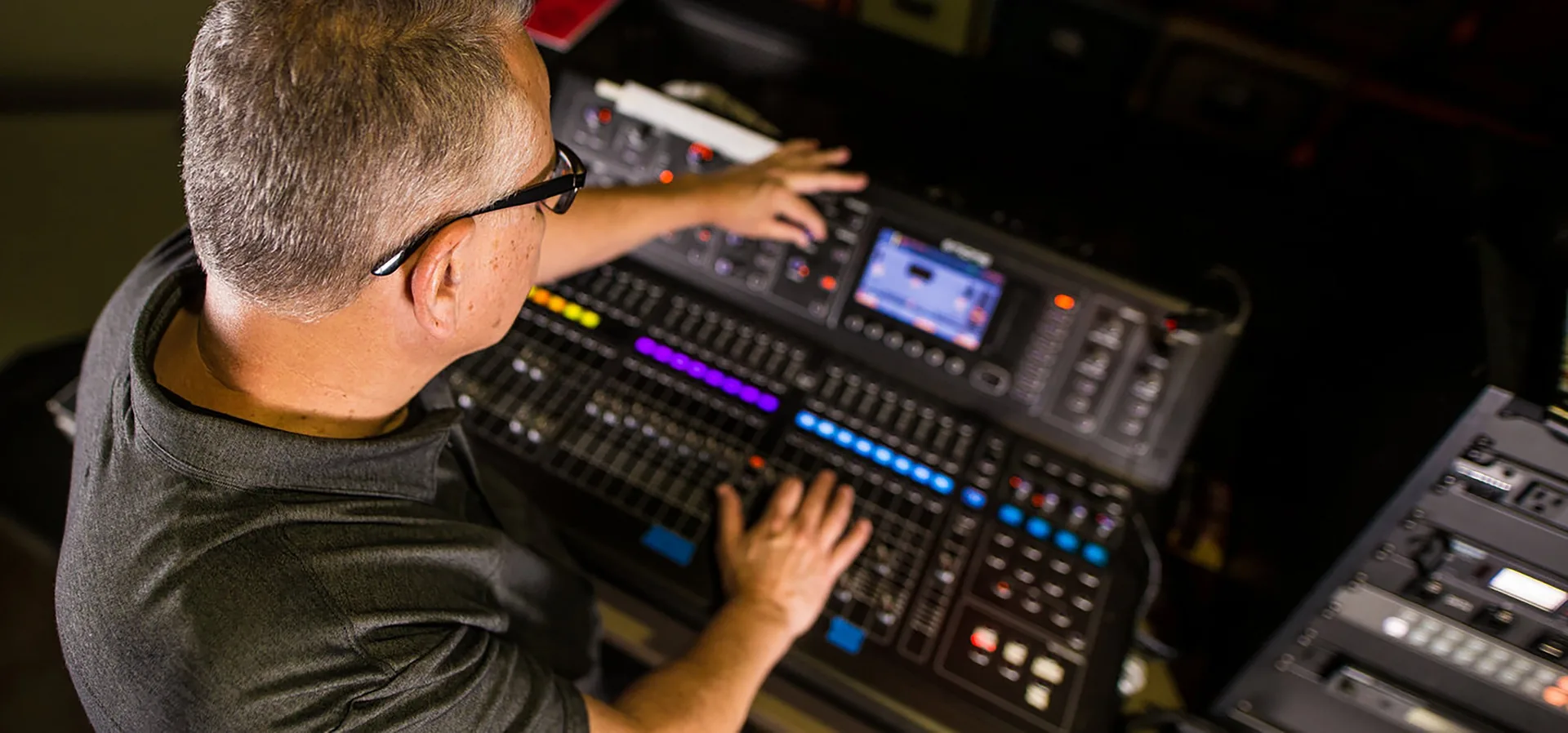 Sound engineer adjusting faders on mixing console during live event