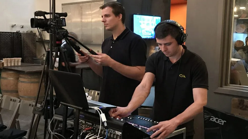 Audio engineers operating AV equipment and mixing console at a live event