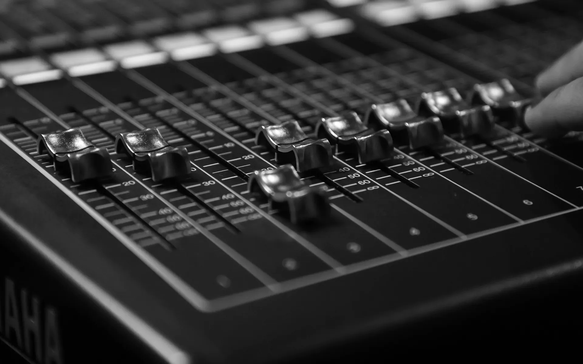 Audio mixer faders controlling amplified sound volume during live event production
