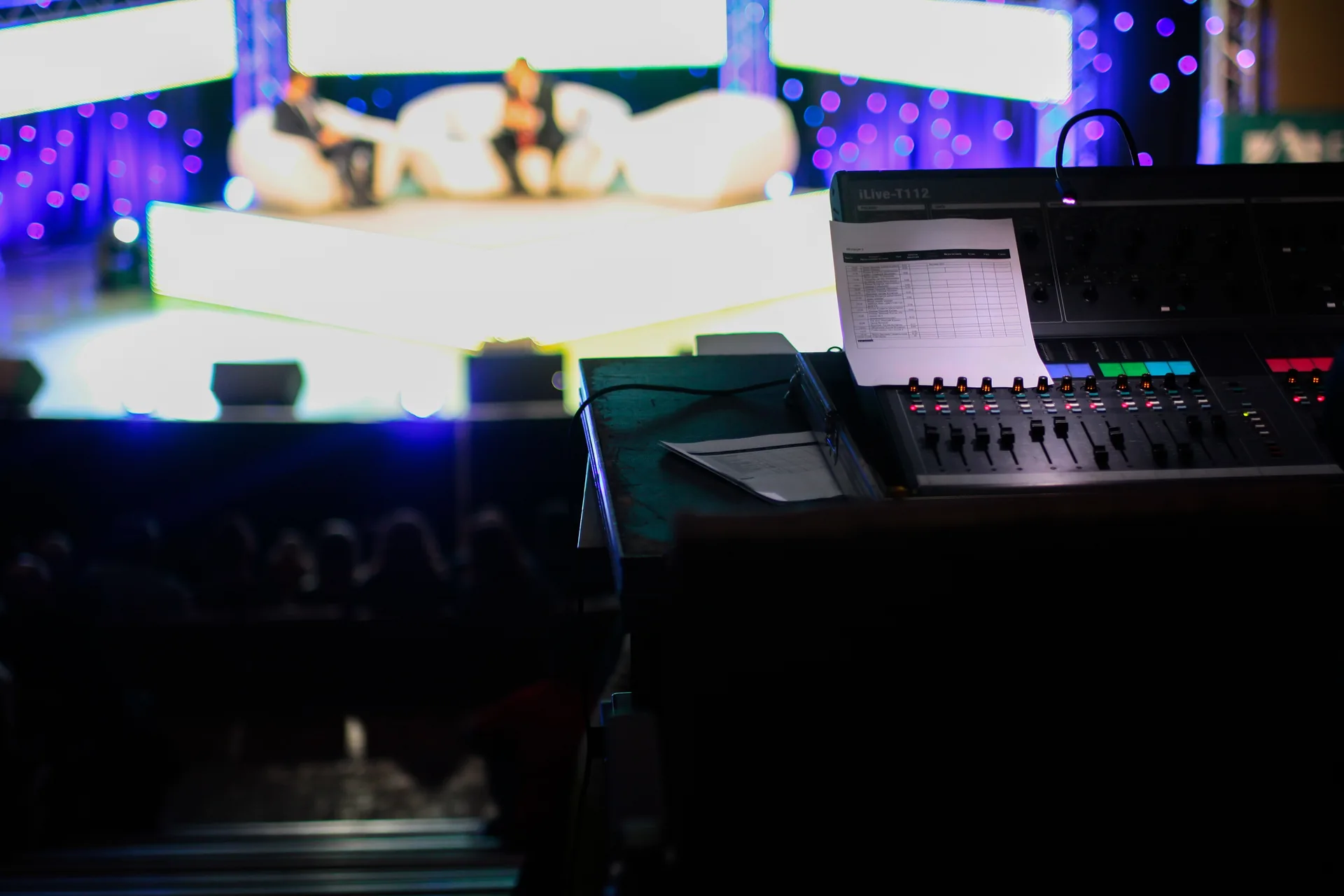 Audio engineer monitoring sound mixer at stage during event production