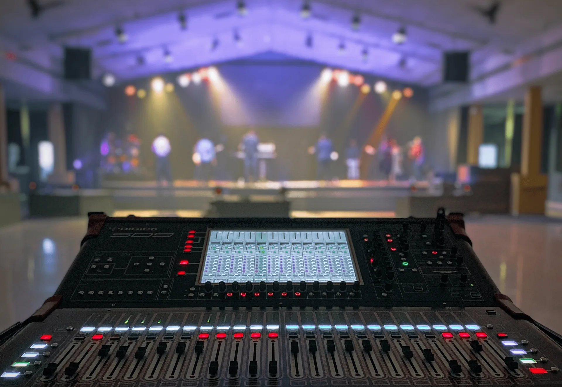 Audio engineer at soundboard mixing band performance on stage