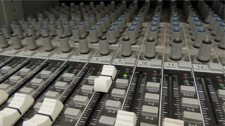 Audio mixer fader controls on a soundboard