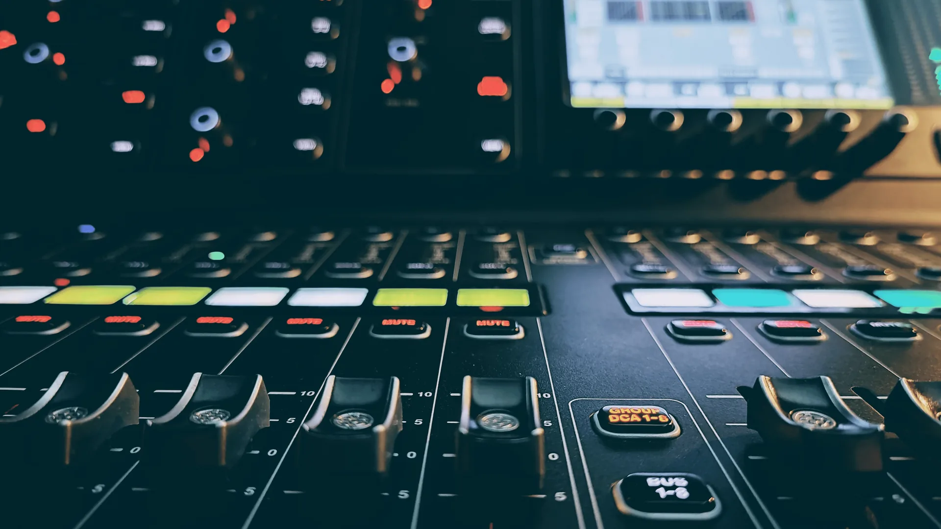 Close up view of an audio mixing soundboard with multiple faders and controls