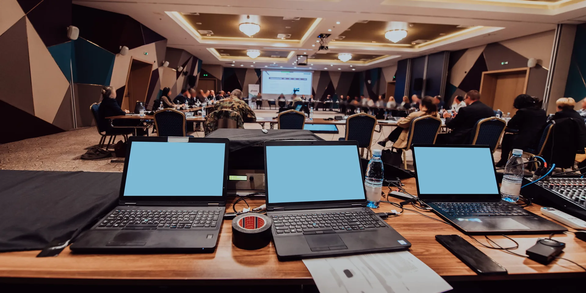 AV control table with laptops and audio equipment managing conference audio recording