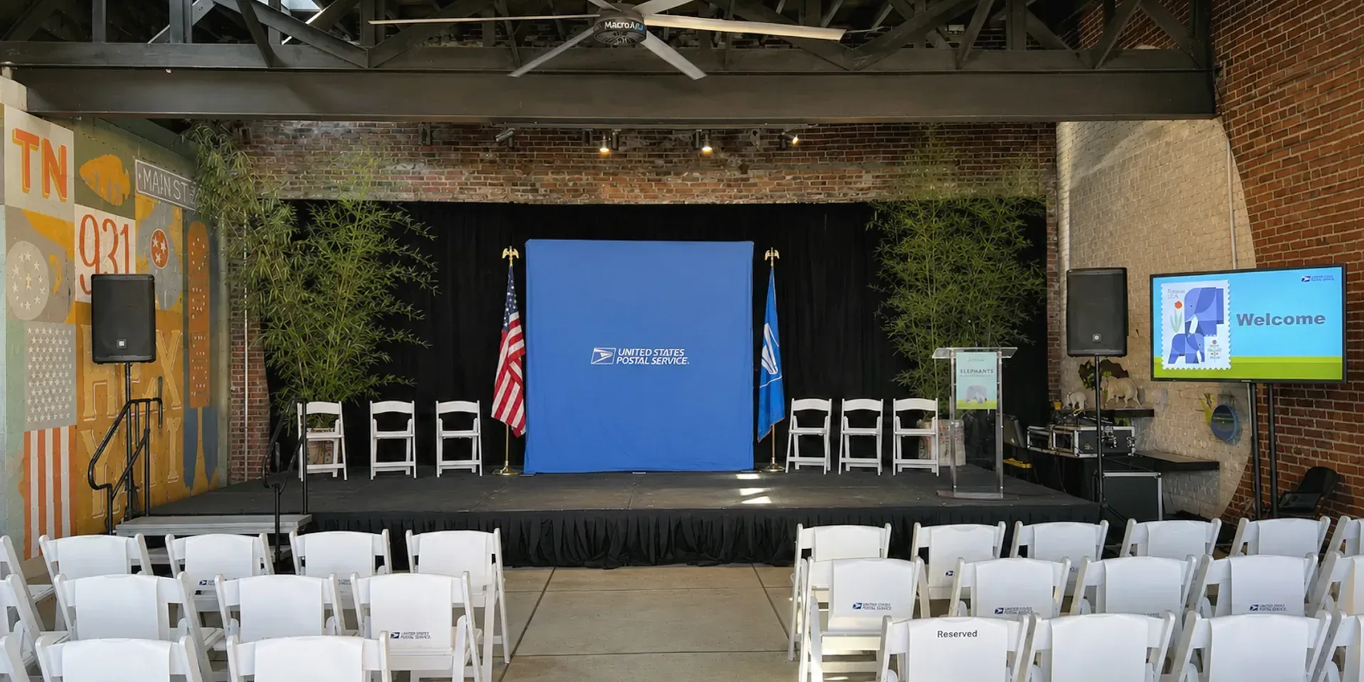 Nashville corporate event setup with PA speakers on stands, clear acrylic podium with microphone and widescreen display monitor