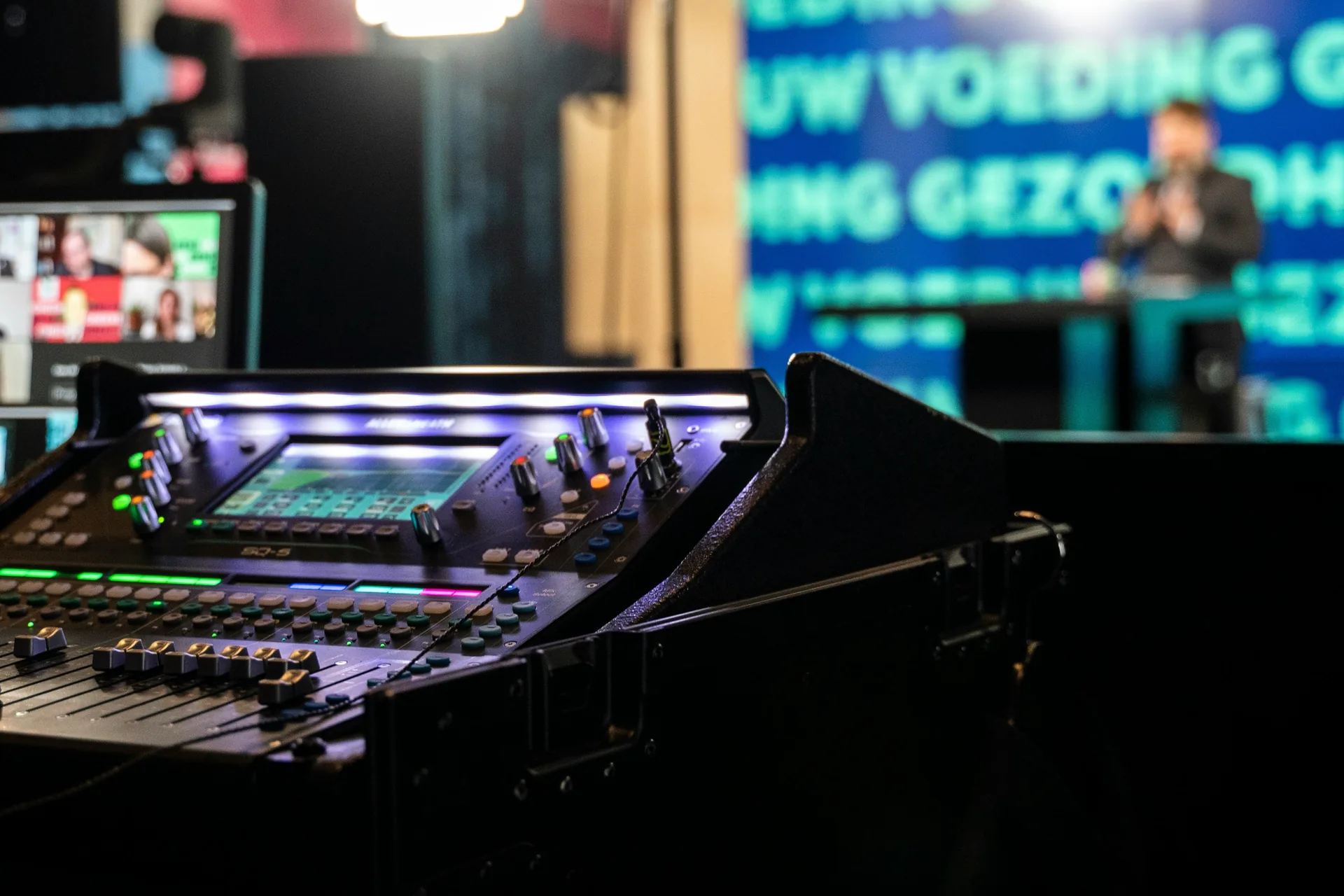 Audio technician operating digital mixing console with multiple faders during live broadcast