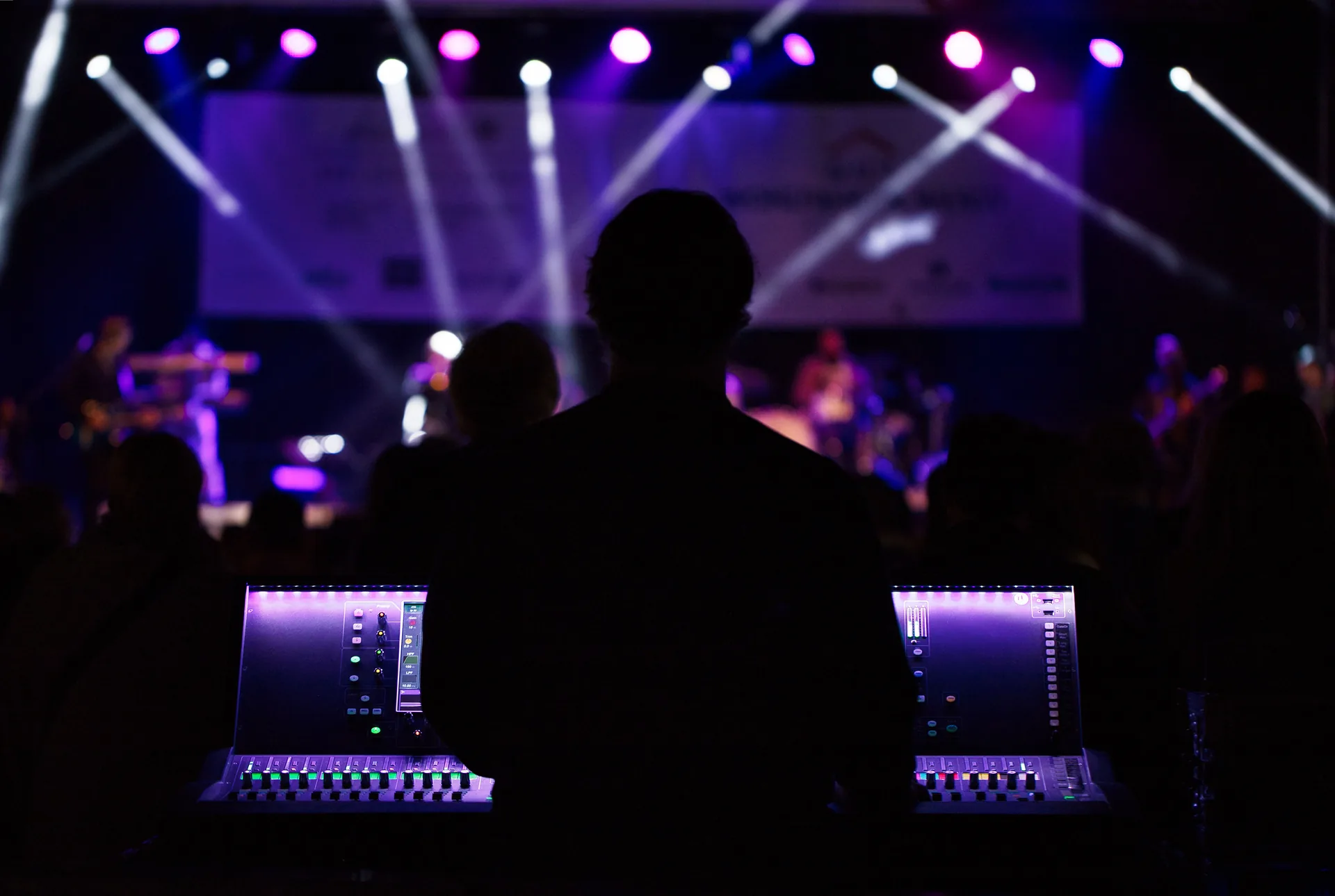 FOH audio engineer mixing sound at front of house position during a live concert