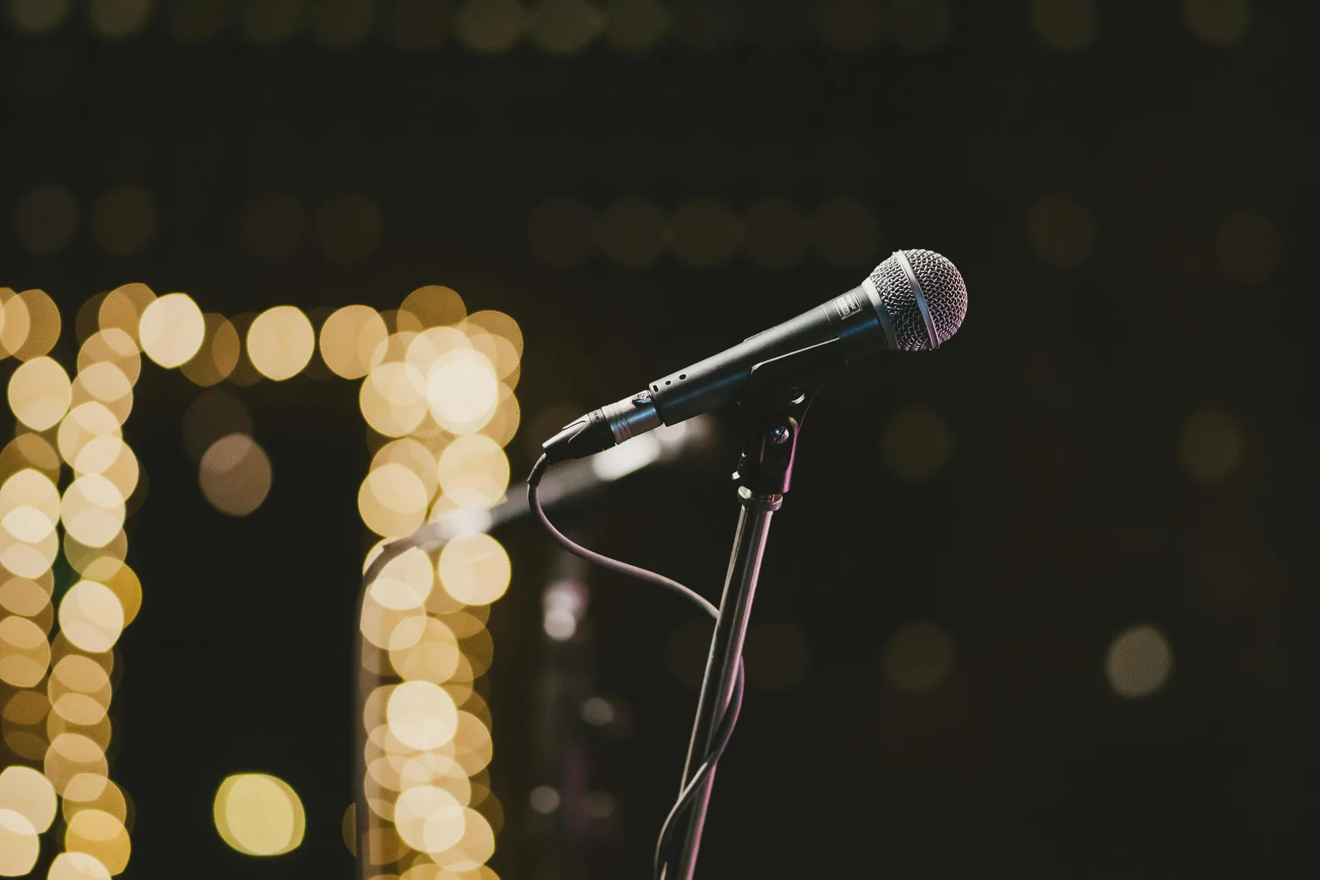 Handheld microphone on a stand with warm bokeh stage lighting