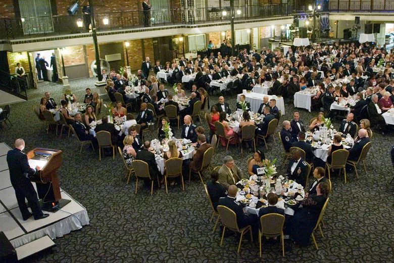 Hotel event space set up for a conference with round tables and a presentation stage