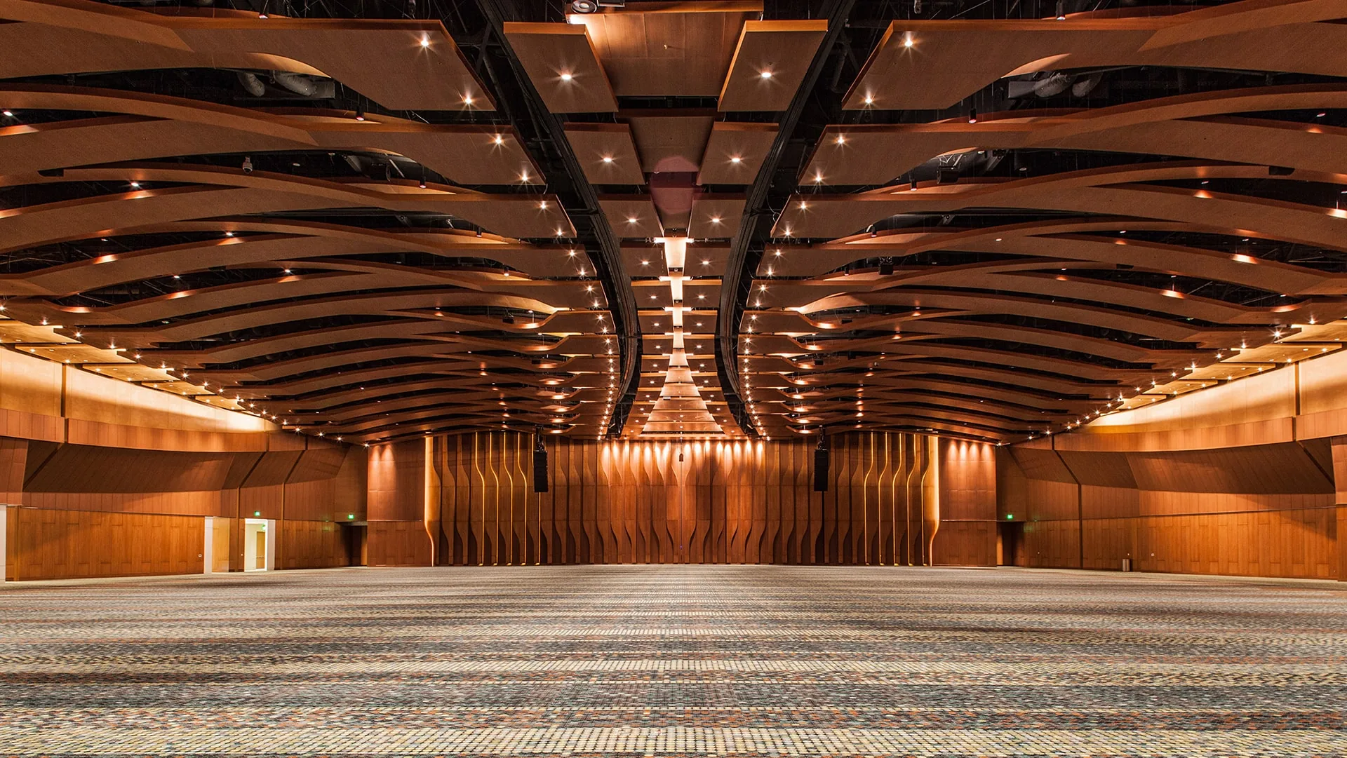 Large conference room with modern layered wooden ceiling, patterned carpet and lighting fixtures