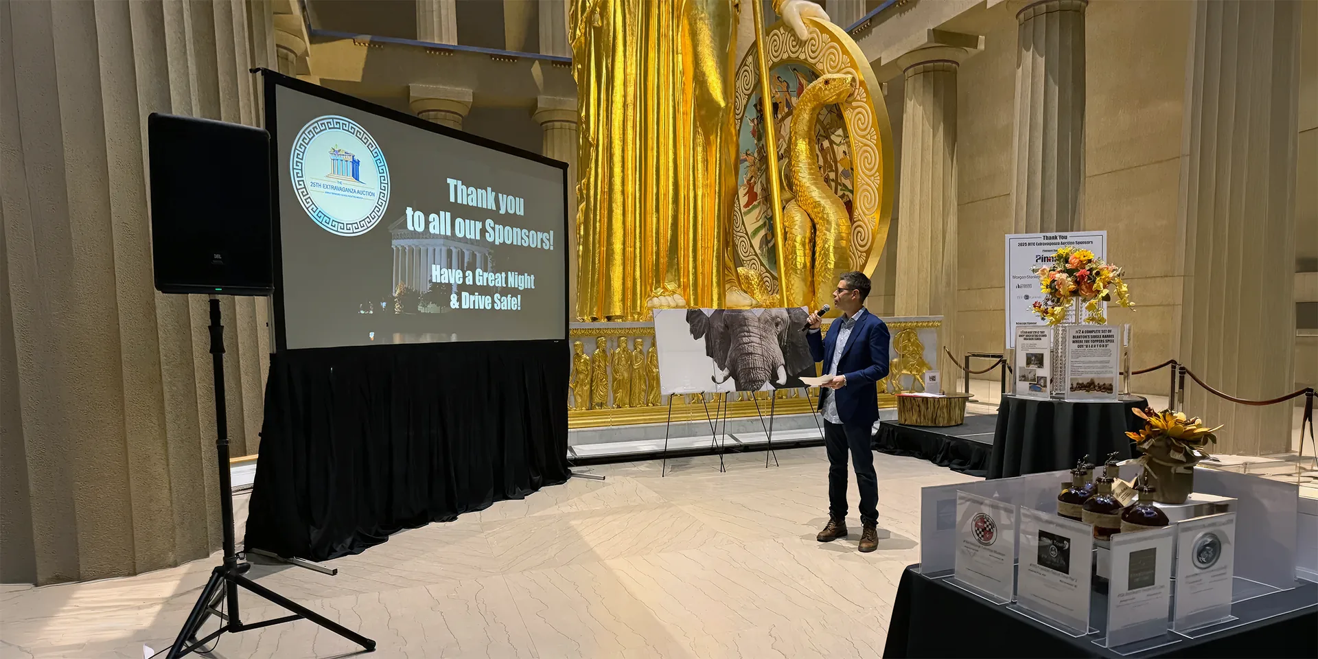 Indoor Nashville event setup with a projection screen, PA speaker and presenter using a wireless microphone.