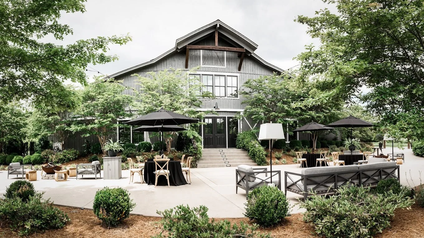 Outdoor event area at Mint Springs Farm with seating, umbrellas and rustic barn building