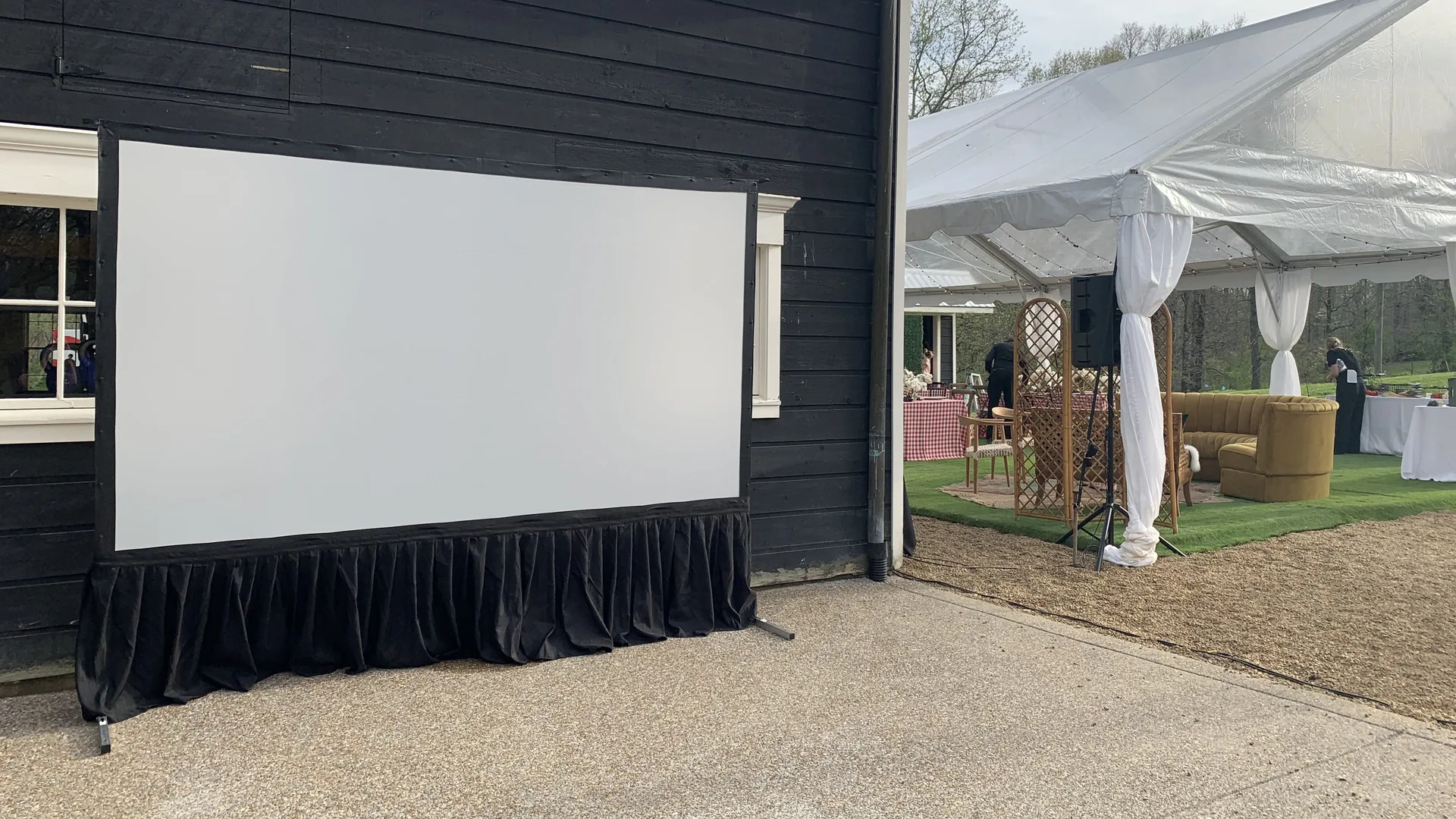 Large projector screen setup outdoors for cinema event with professional AV equipment