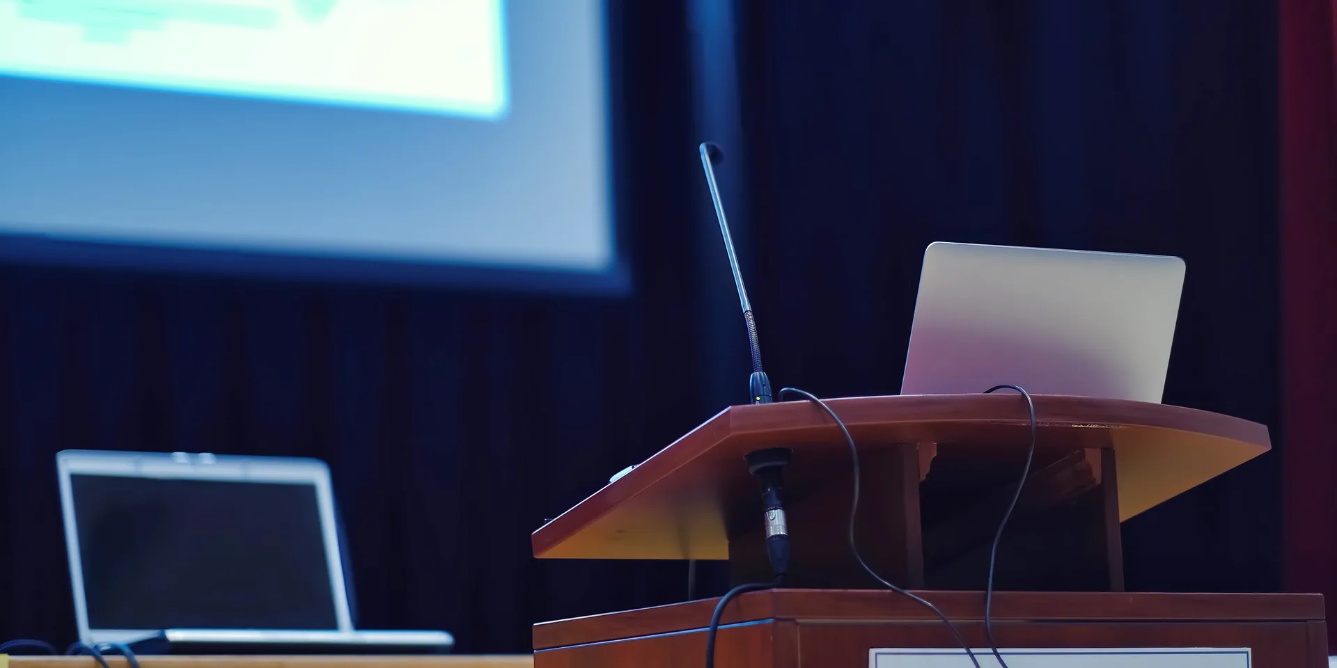 Conference stage podium with presentation laptop and microphone ready for speaker