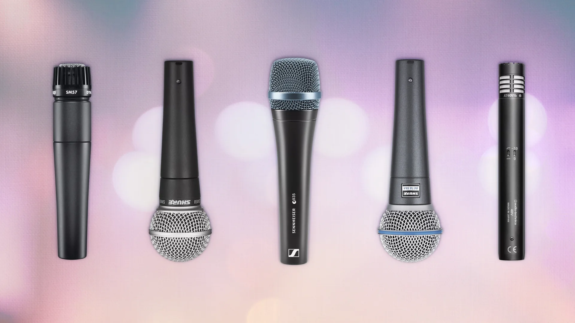 Five professional microphones in a row against a soft purple and pink bokeh background for event rental