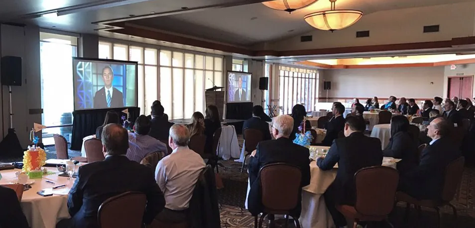 Projector mounted above screen with audio speaker system at conference