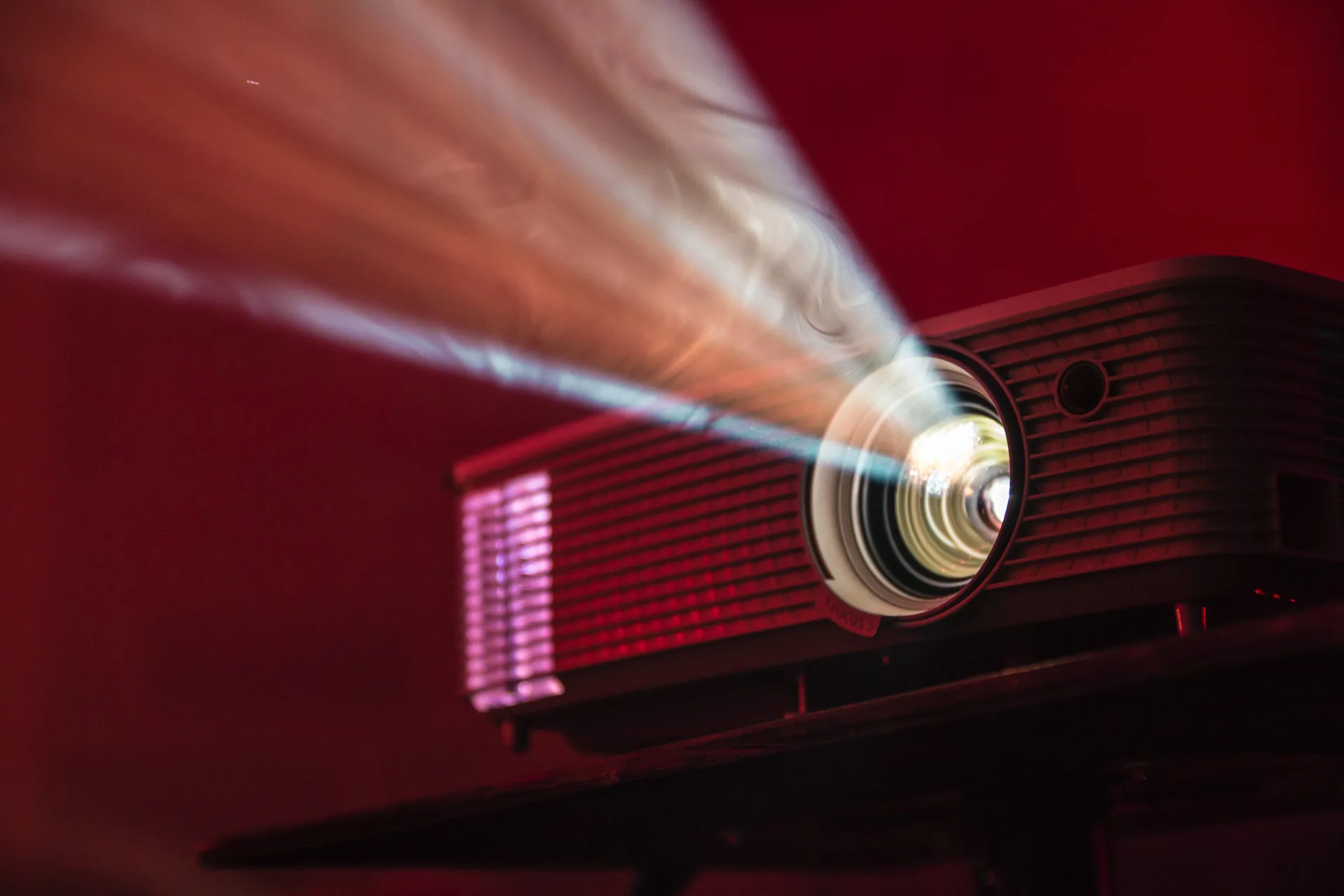 HD projector casting bright light beams through smoke in dimly lit venue space