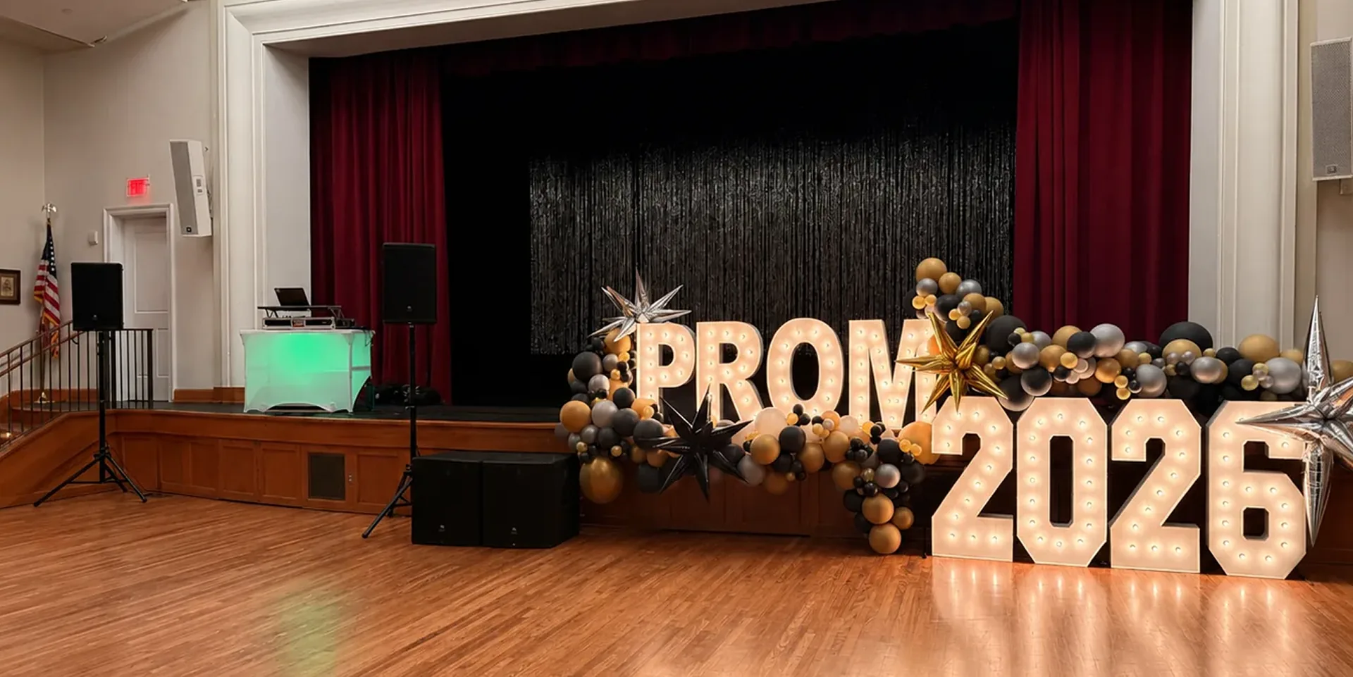 Prom event stage setup with tripod-mounted PA speakers and subwoofers for live event audio