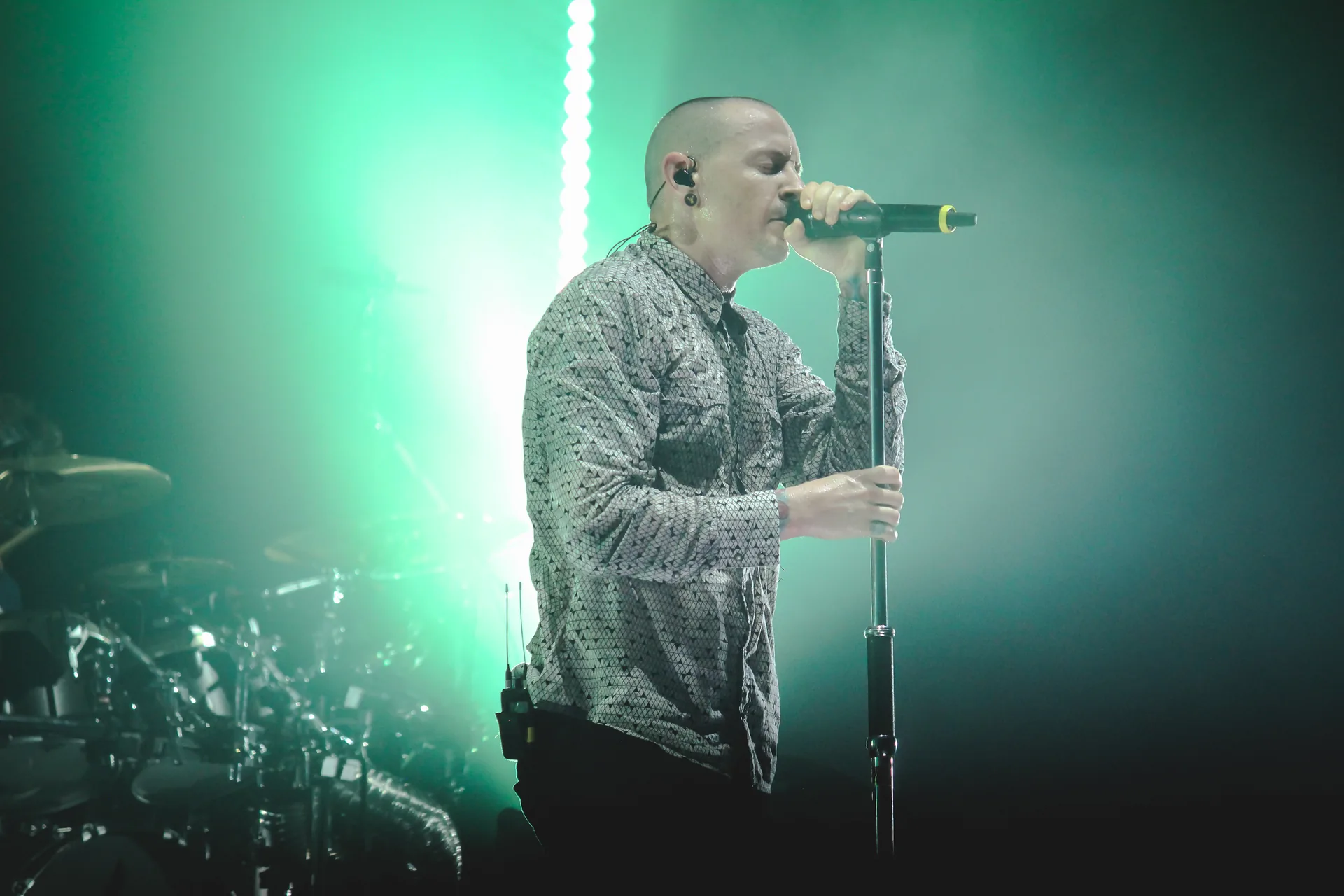 Male singer at concert performing with wireless microphone and in-ear monitor system