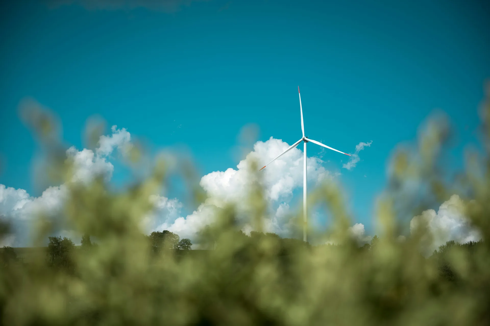 Single wind turbine standing against clear blue sky representing renewable energy source