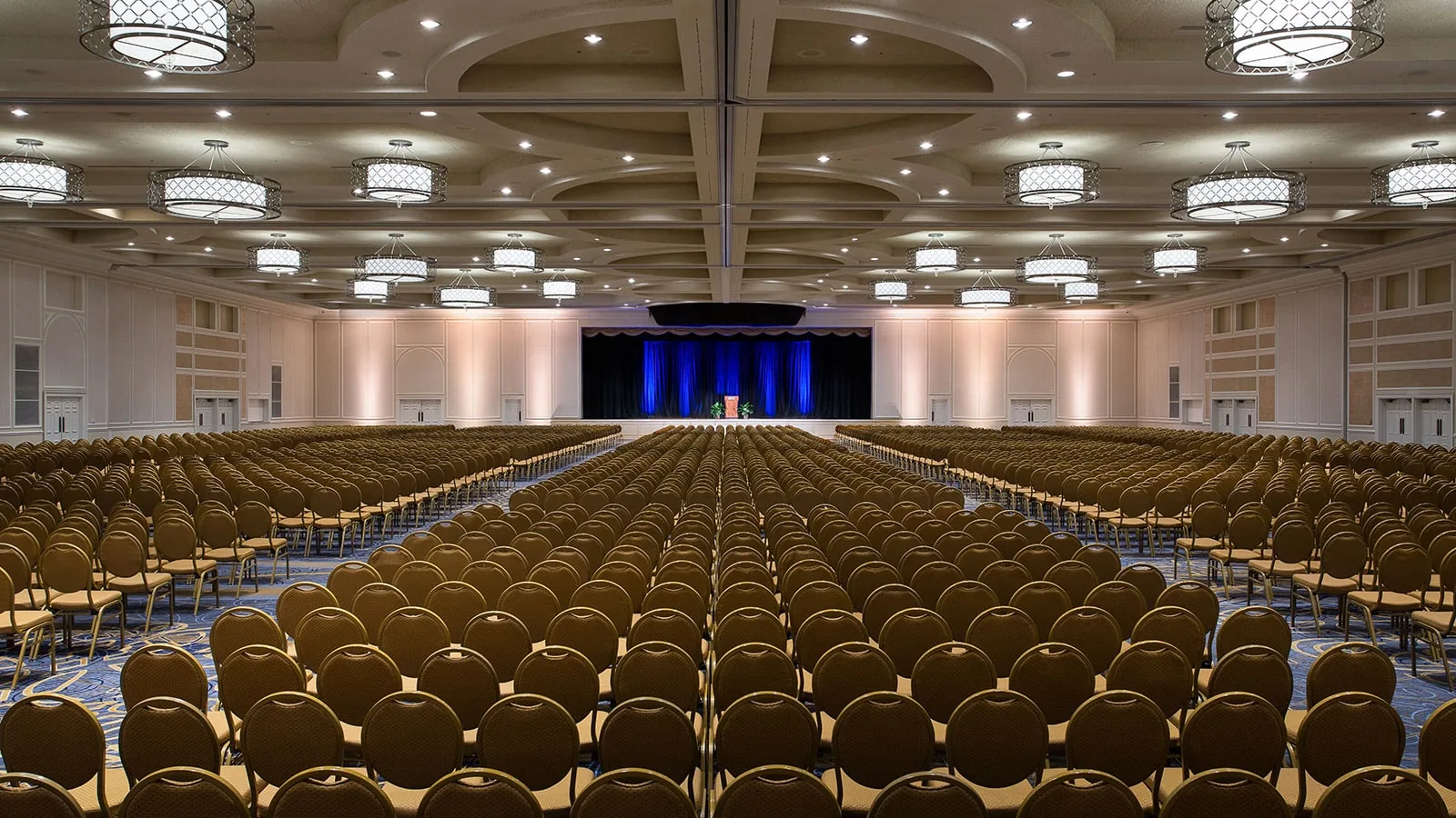 Large conference hall with rows of chairs facing stage with blue curtain at Gaylord Opryland