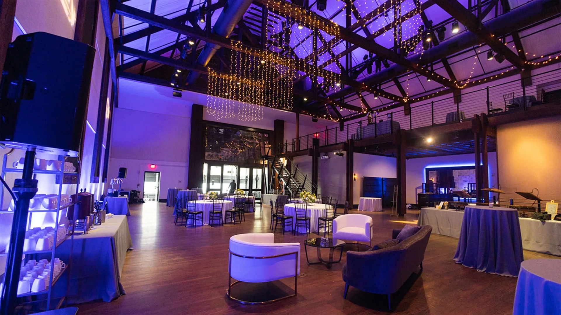 Spacious Bell Tower interior with high ceilings, string lights, modern furniture and dining tables