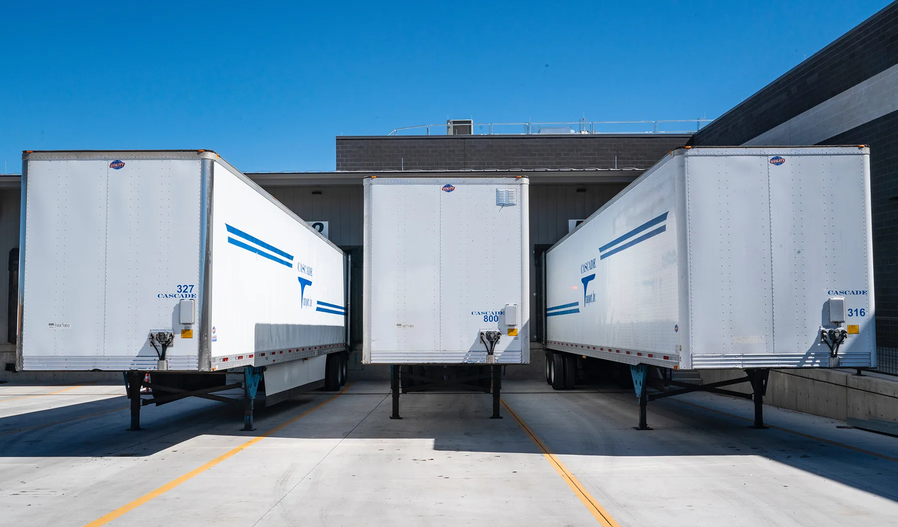 Three semi-trailers docked at an event venue for simultaneous vendor load-in