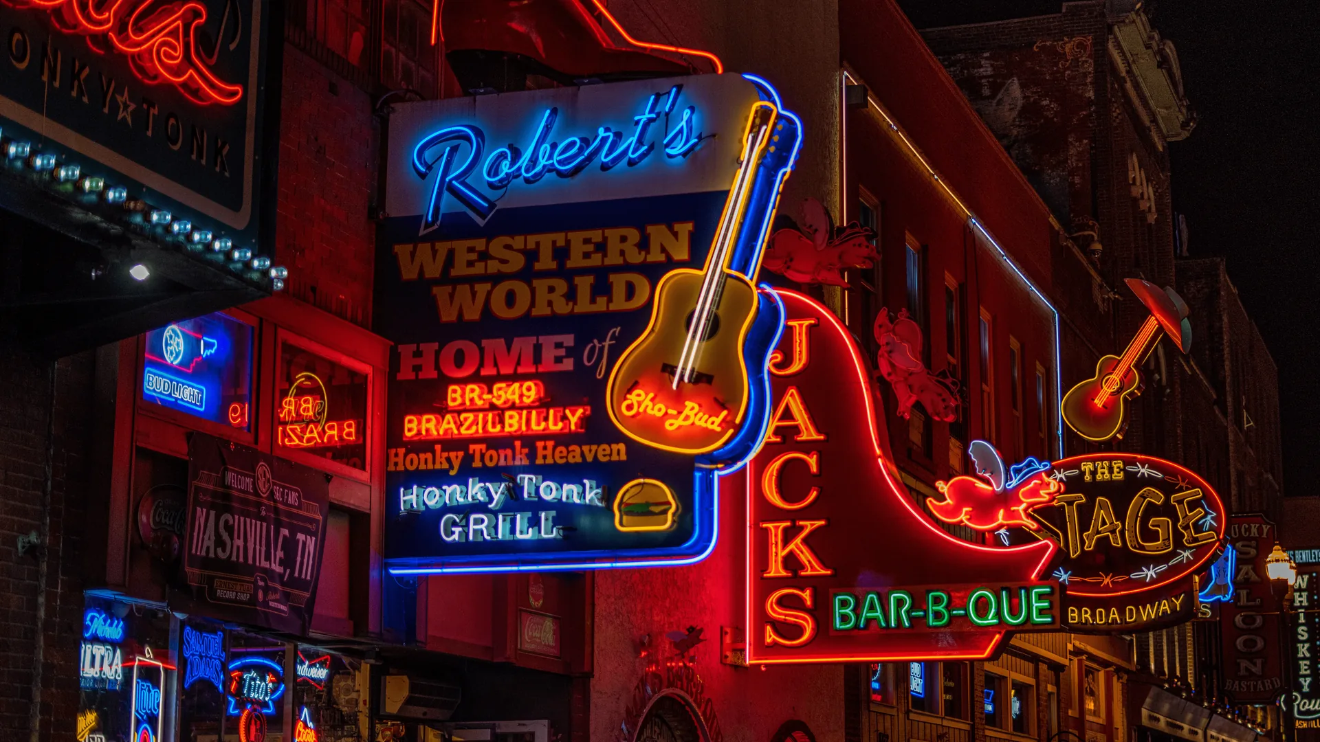Nashville Broadway street at night lined with neon signs and honky tonks