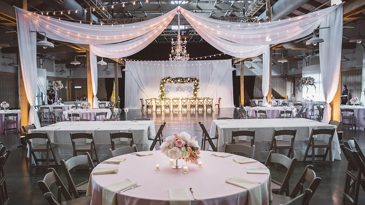 Wedding reception setup with decorated tables, floral arch and draped ceiling at Loveless Barn