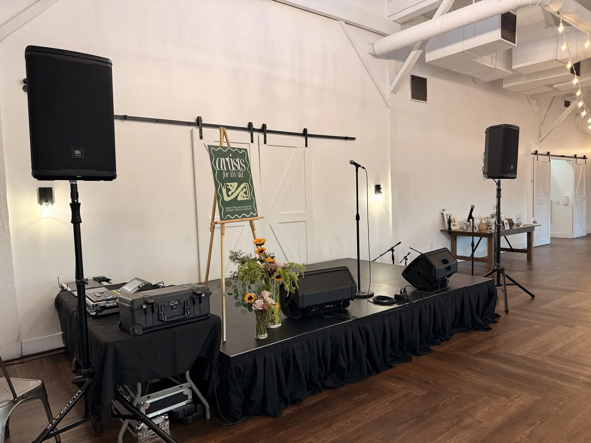 Close view of Channel AV audio setup with PA speakers, mixer and floral stage décor for Artists for AWAKE