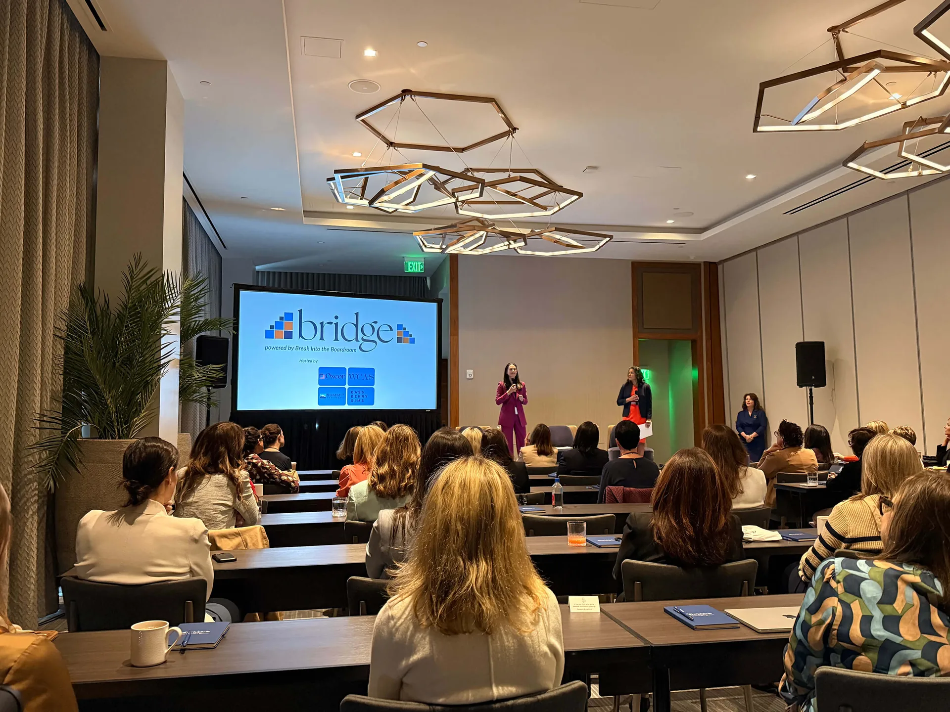Panelists presenting to an audience at a corporate conference with PA audio and a projection screen