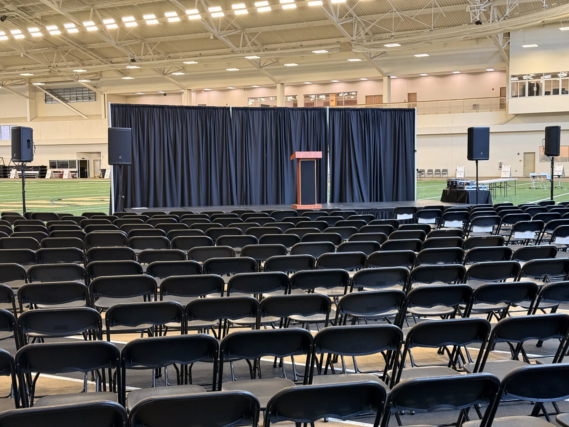 Audience seating facing a corporate presentation stage with podium and professional PA speaker system