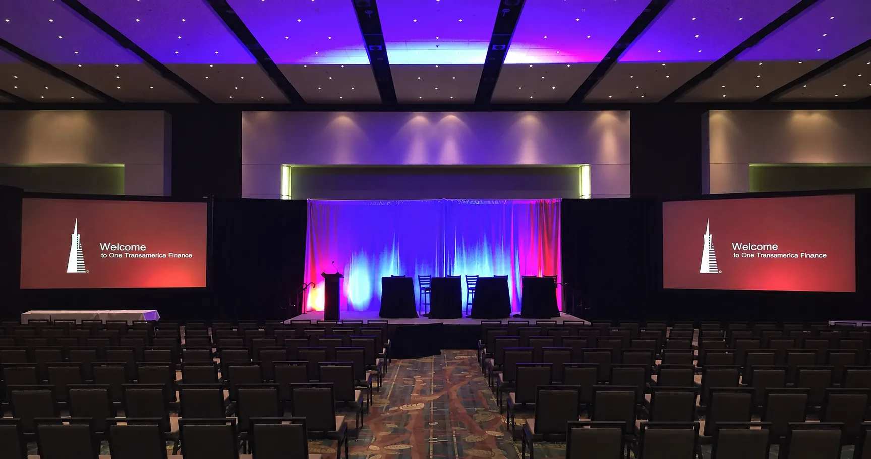 Hotel ballroom stage with projection screens and black pipe and drape for a corporate conference in Nashville
