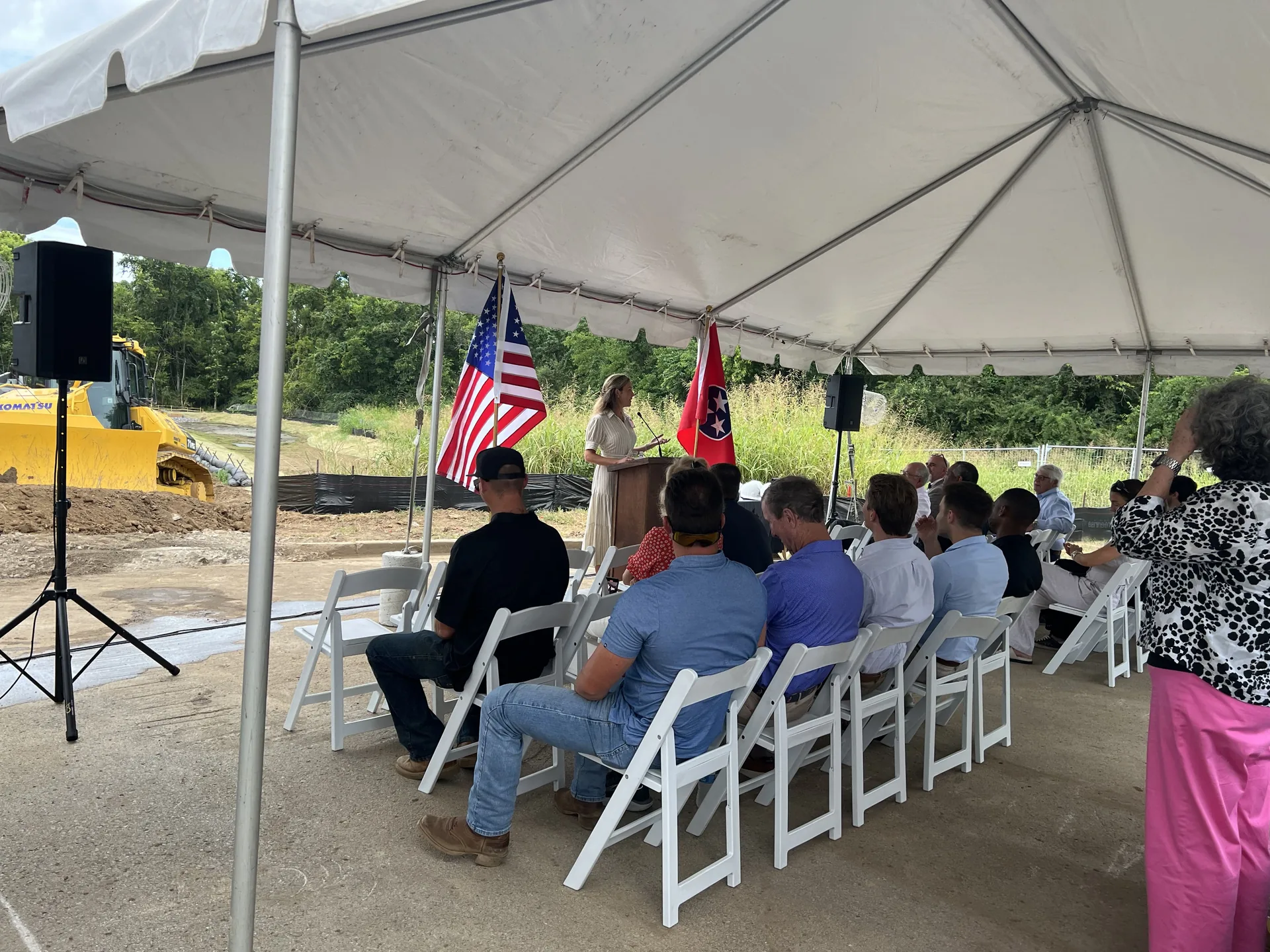 Groundbreaking ceremony presenter addressing the audience through a PA system under a tent
