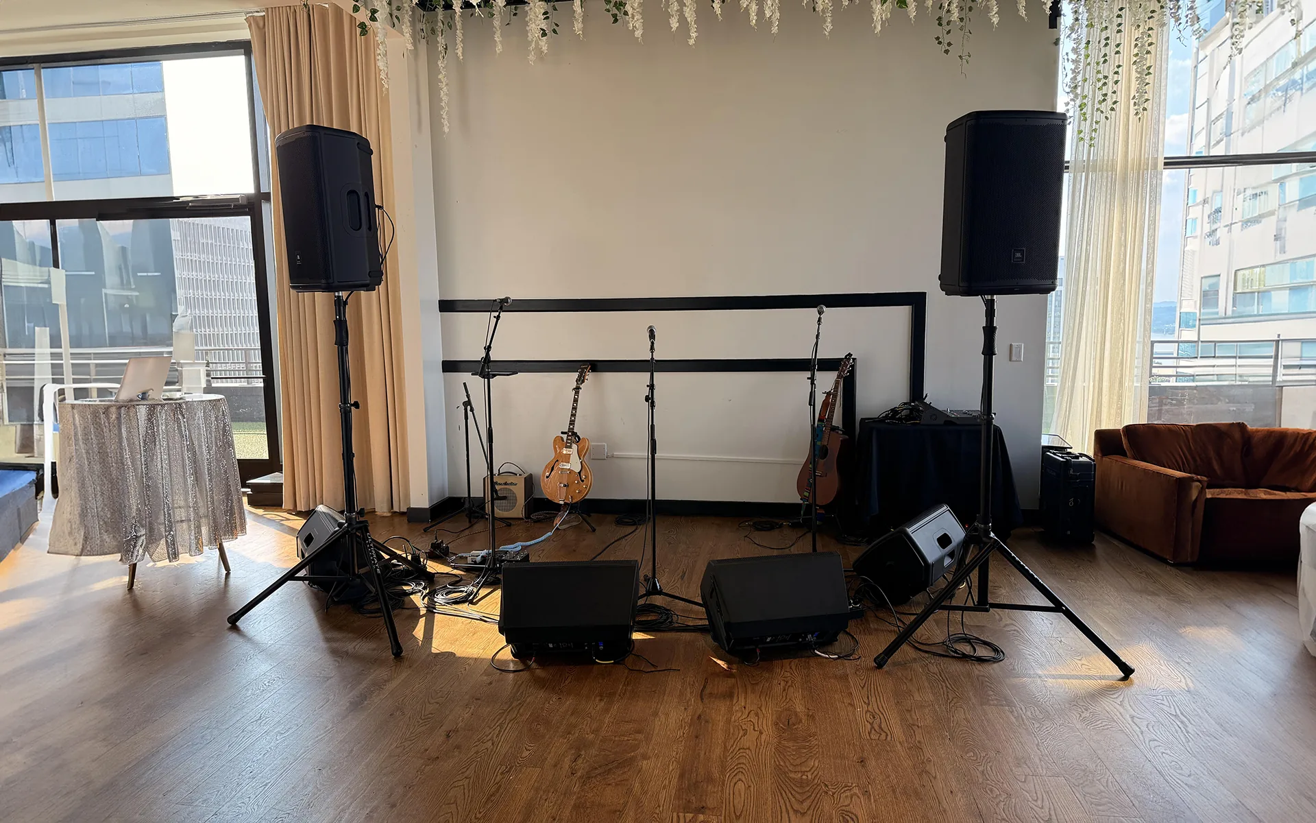 Indoor live music stage setup with PA speakers, floor monitors, microphone stands and audio mixer