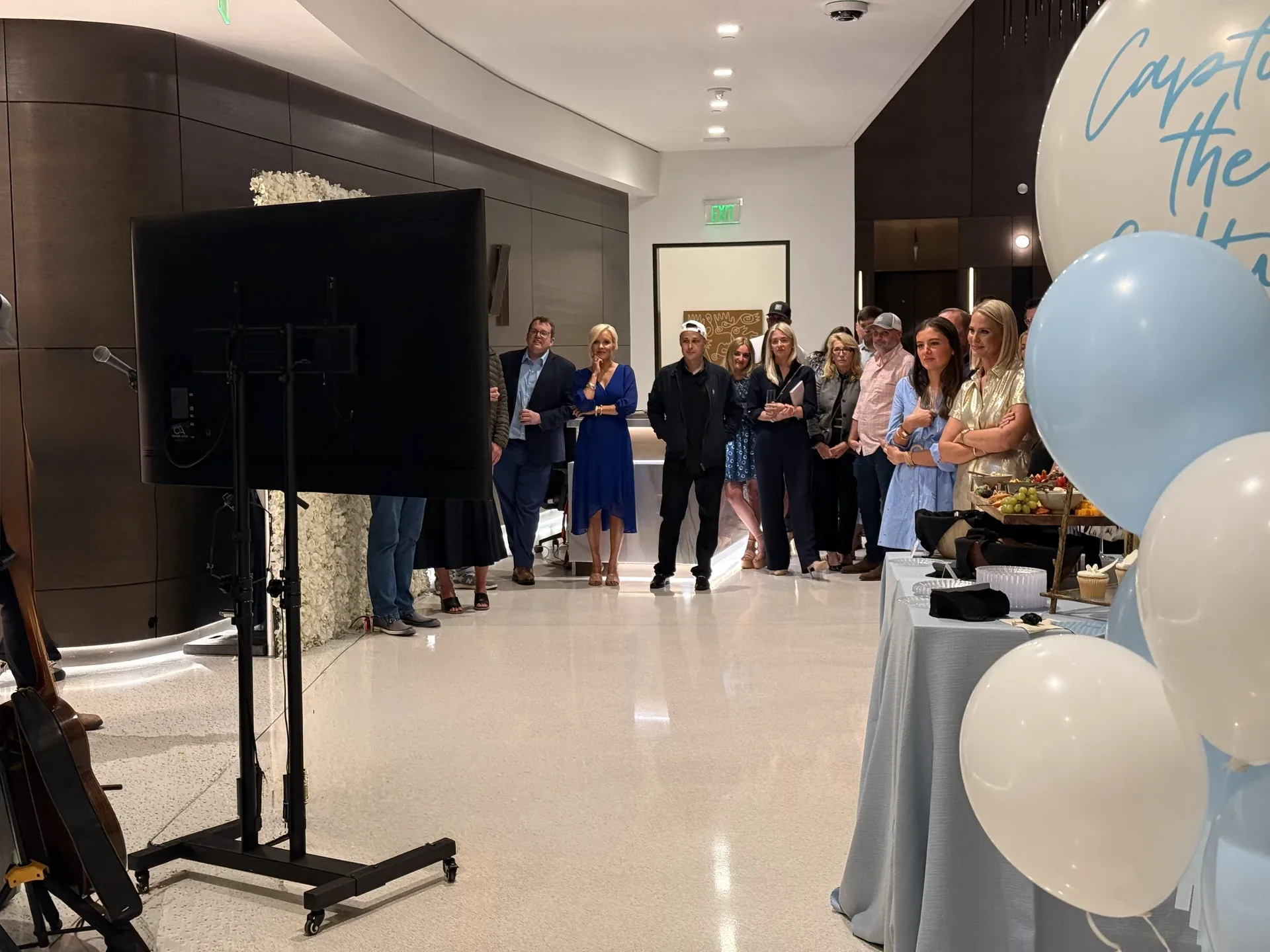 Crowd watching a presentation on a TV display inside a modern event space