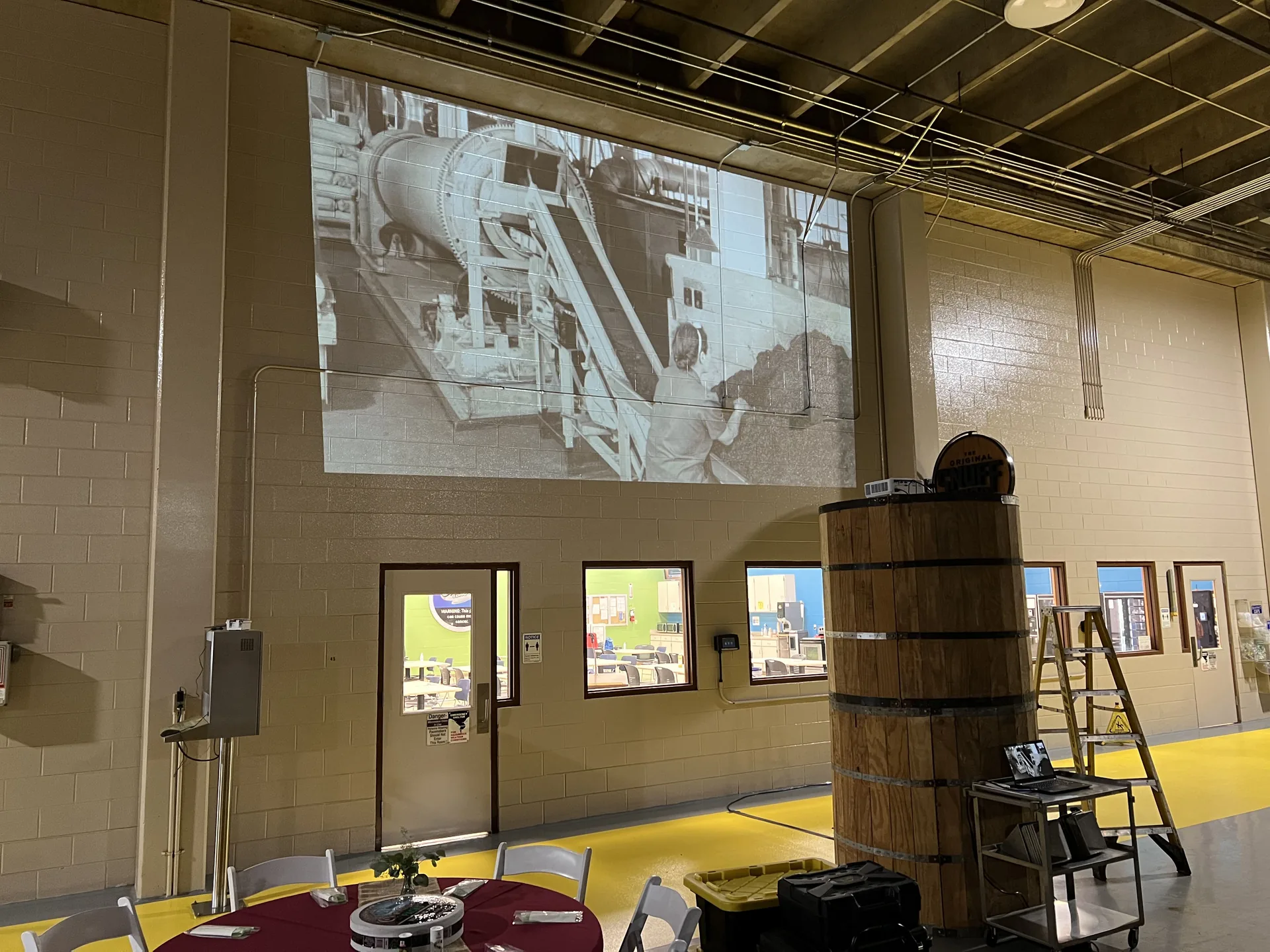 Industrial space with historical images projected on the wall during an event with round tables