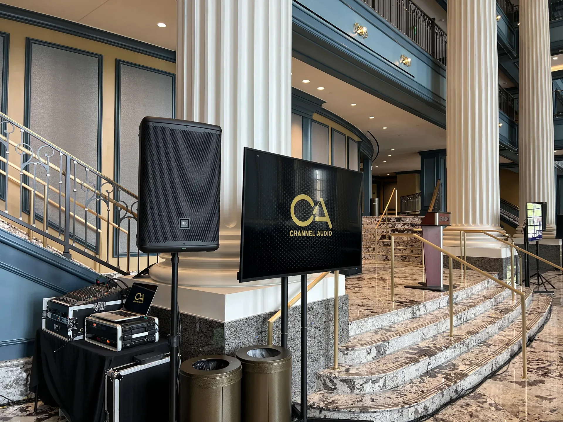 Lobby AV setup with TV display, PA speaker and audio rack beside classical columns