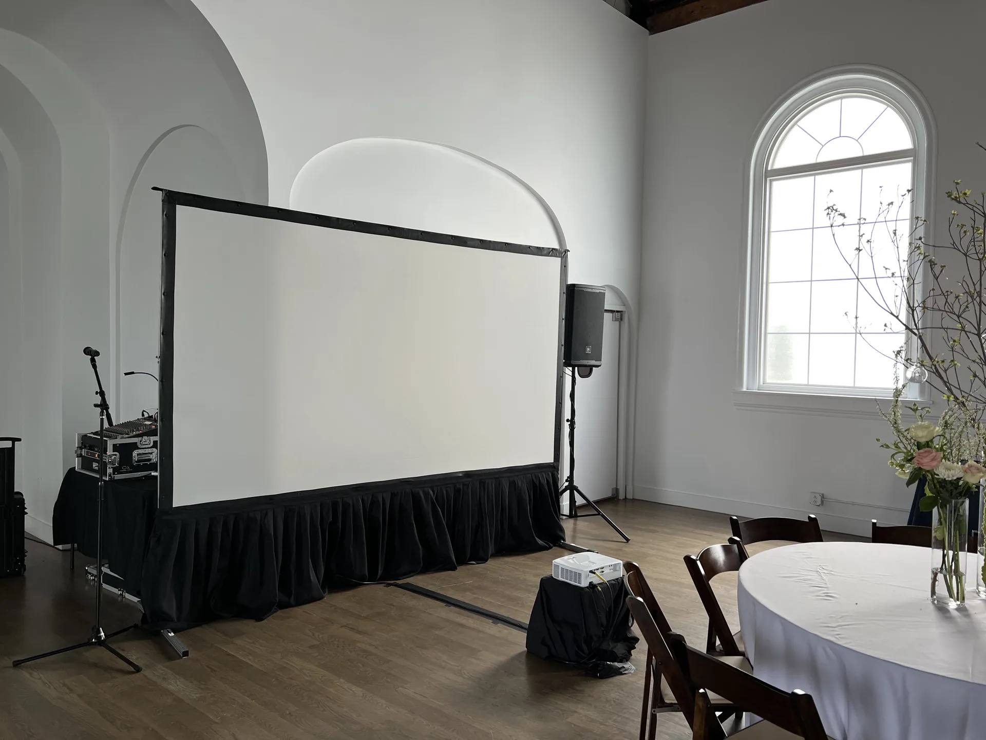 Minimalist conference room with a large projection screen and PA audio system