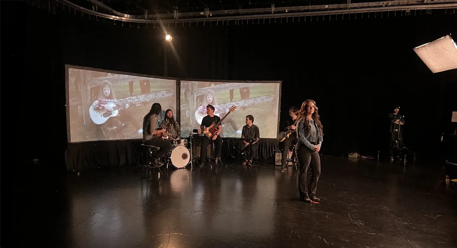 Band performing with projected visuals in the background during a music video production