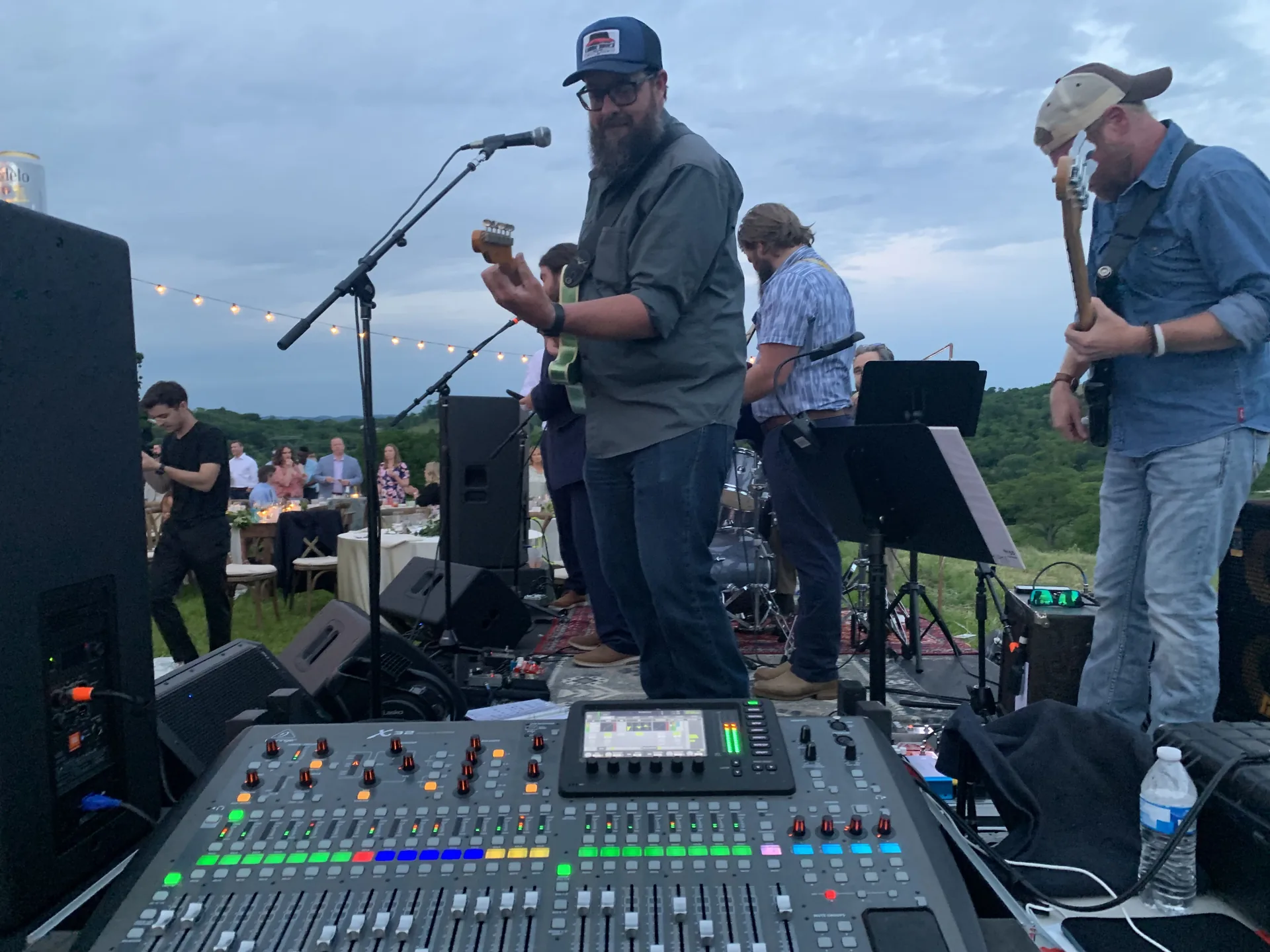 Outdoor band performance with musicians playing guitars and audio equipment setup