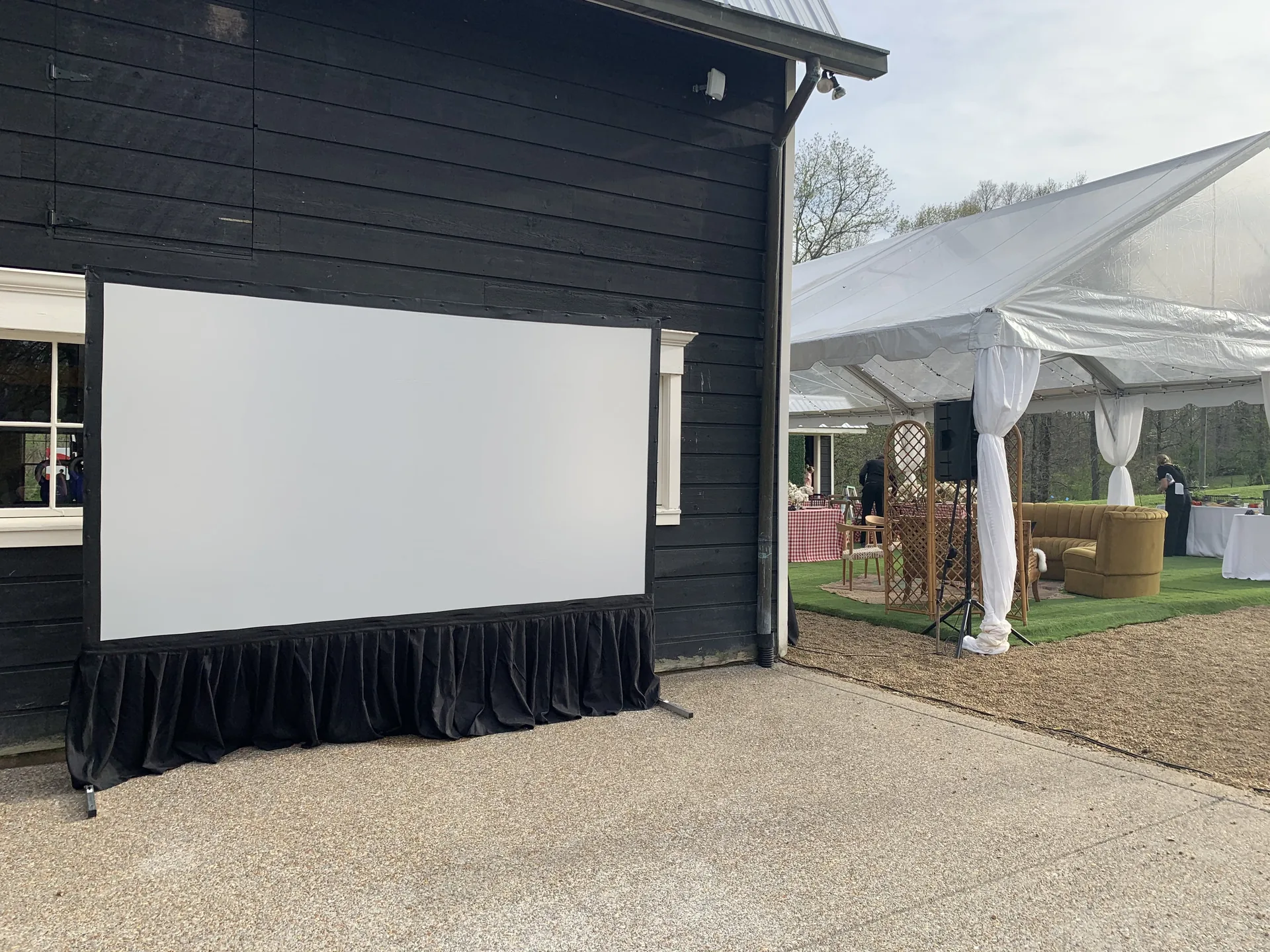 Outdoor cinema screen setup next to a black barn