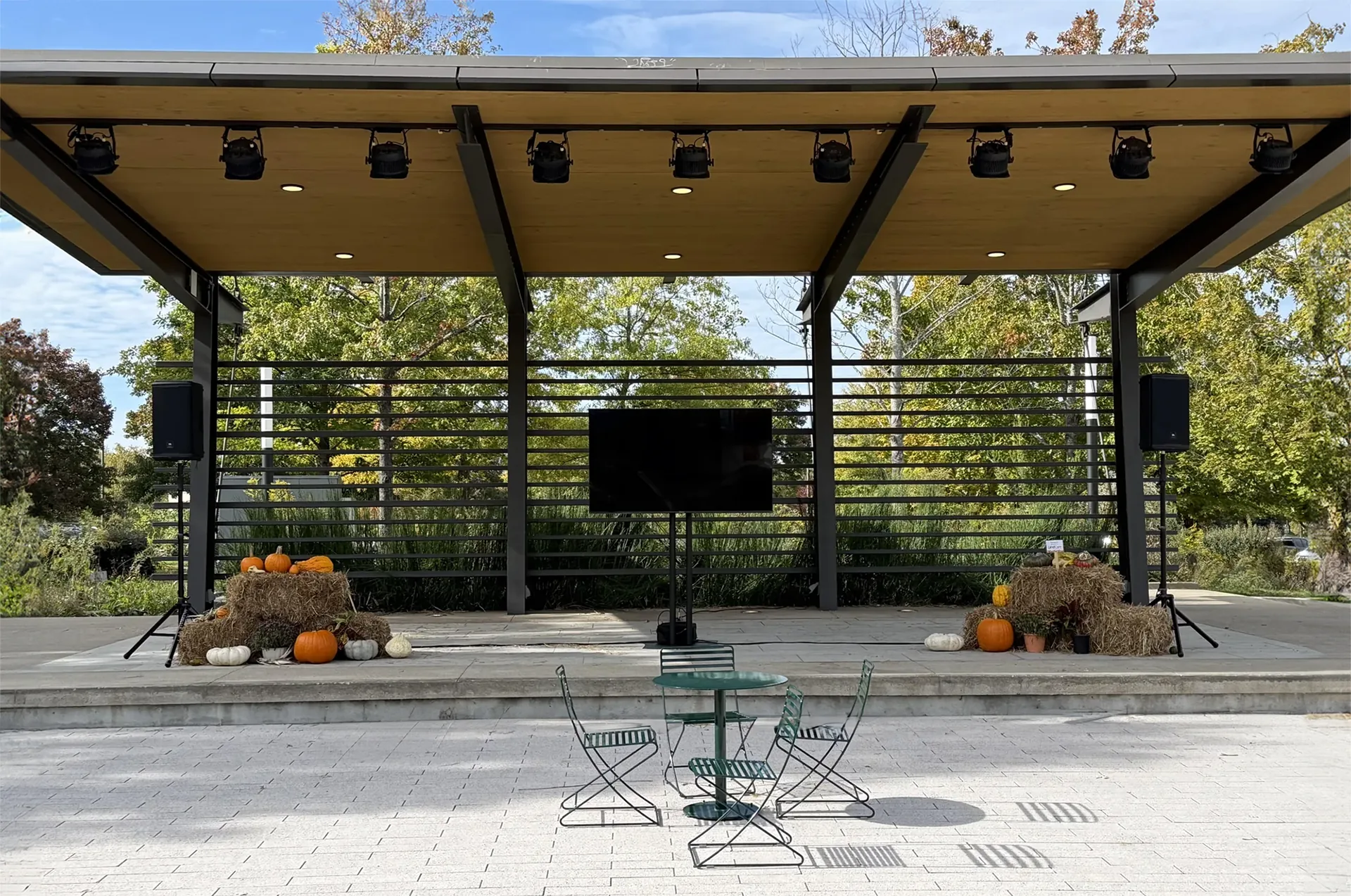 Outdoor stage with hay bales, pumpkins, and TV display prepared for fall event presentation