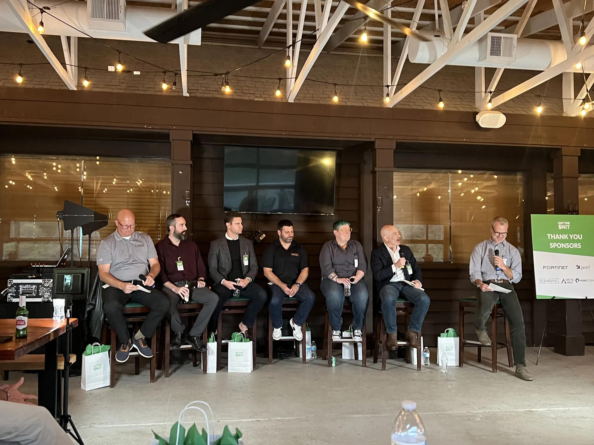 Six-person panel discussion with a PA audio system under string lights