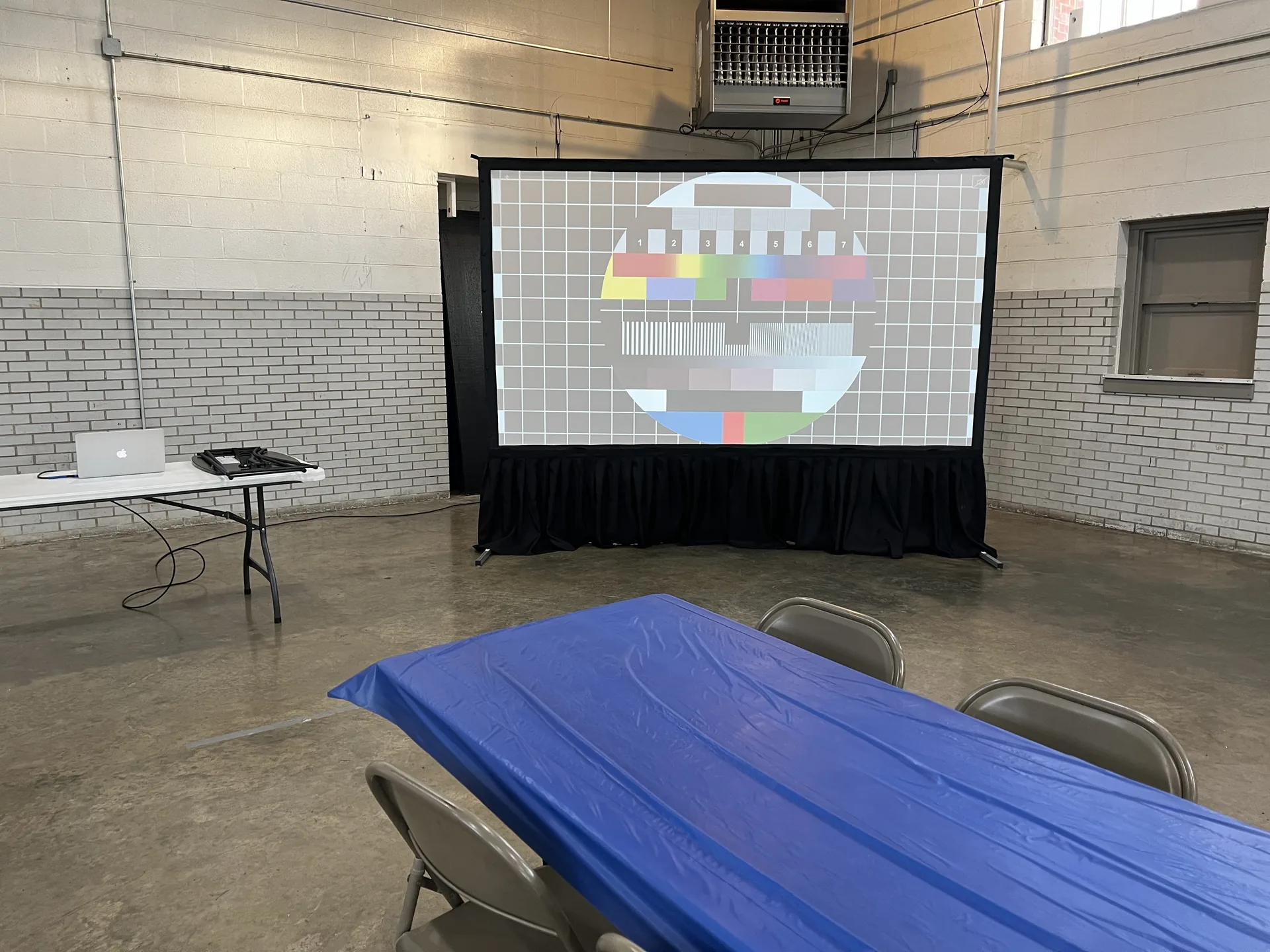 Projector test pattern displayed on a screen in an industrial event space with brick walls